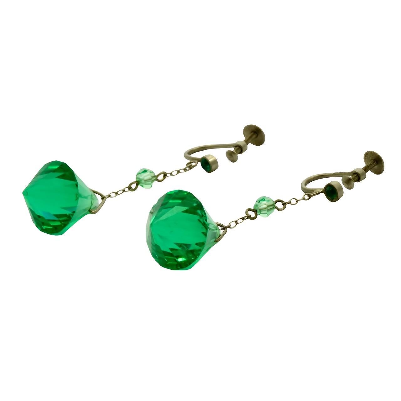 Beautiful Art Deco silver tone earrings featuring lovely emerald green faceted glass drops. They have screw back fittings. Measuring length 4.6 cm / 1.8 inches.

This pair of stylish Art Deco emerald green glass earrings is circa 1930s. They look