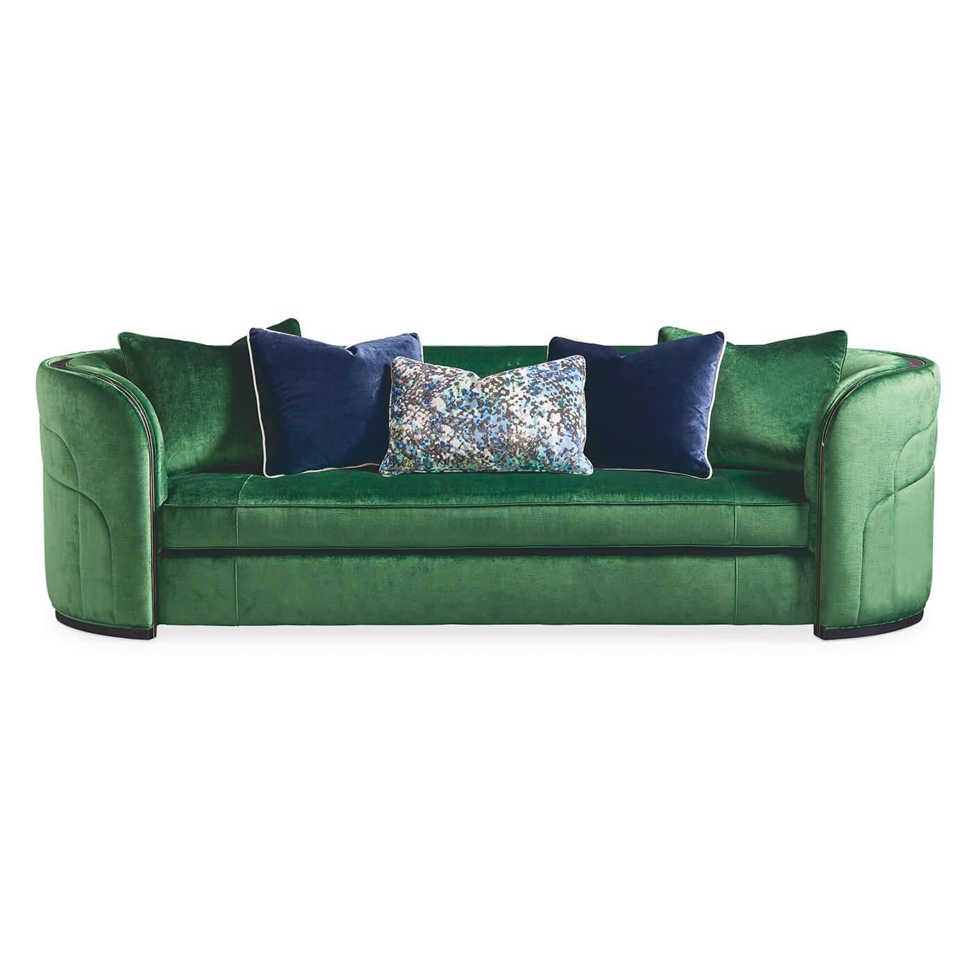 French Art Deco style emerald sofa. This sofa is glamour personified! Couture detail, a contemporary curving silhouette and fashionable upholstery define this eye-catching sofa. It's upholstered in vibrant emerald green velvet with plush pillows in