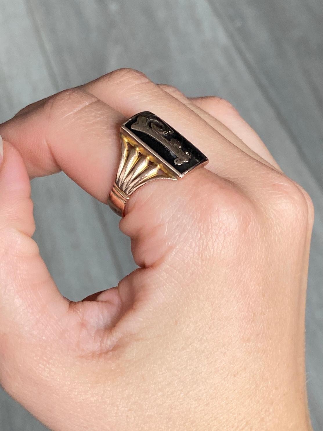 Dieser Ring enthält eine rechteckige Emaille mit dem Buchstaben 