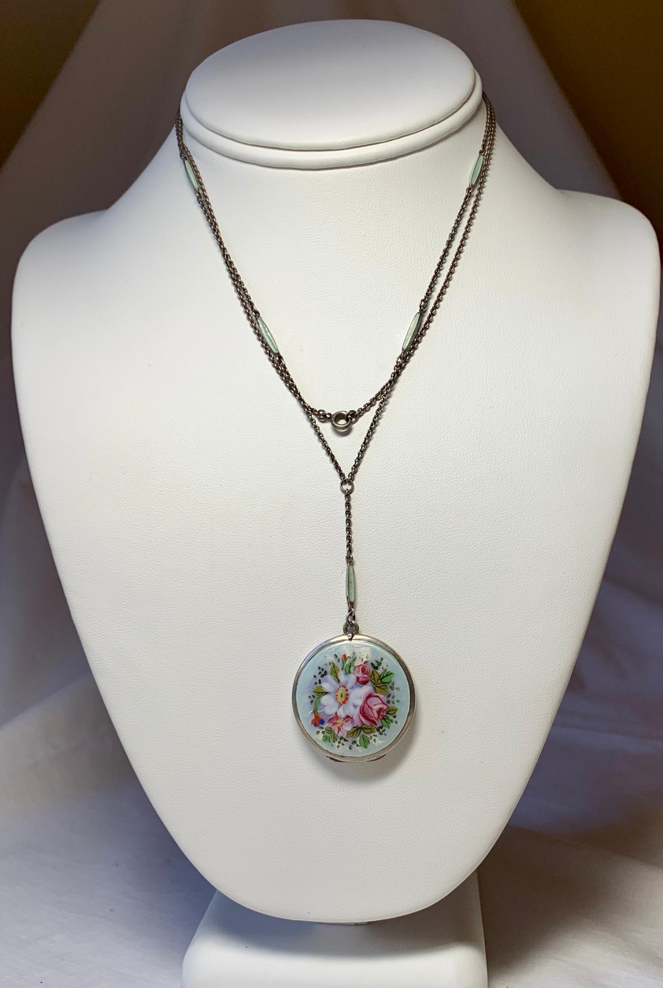 A rare and wonderful Edwardian locket pendant necklace with gorgeous guilloche enamel in a pale blue green color over Sterling Silver.  A stunning flower bouquet in hand painted enamel decorates the front.  The guilloche enamel continues on five