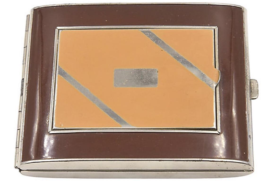 Art Deco two-tone brown enamel compact cigarette case. The top section lifts up to reveal a mirror and a section for blush and an additional area that lifts up to reveal powder; both areas retain the original puffs. The cigarette holder in the back