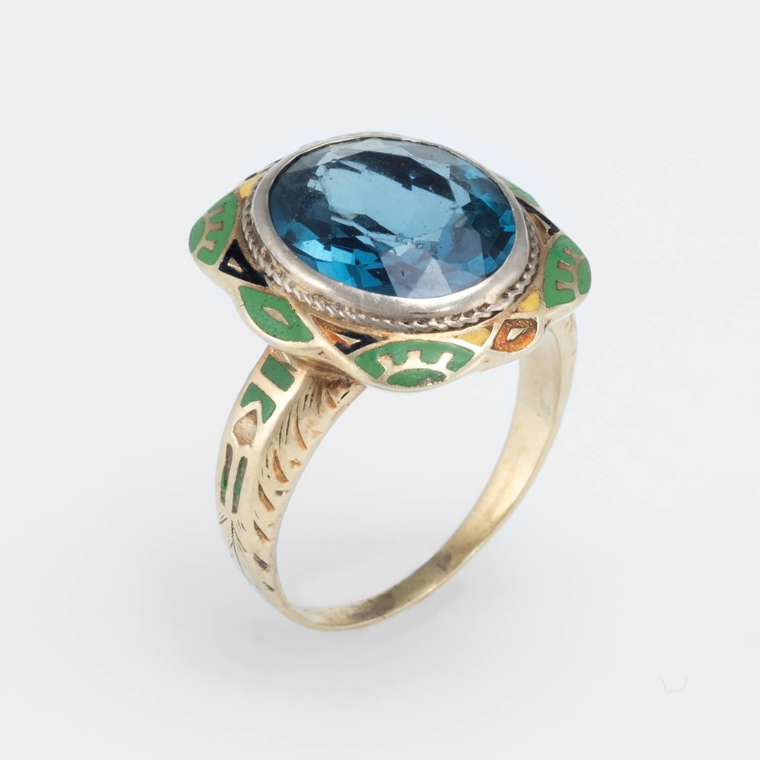 Overview:

Vintage Art Deco era enamel cocktail ring (circa 1920s to 1930s) crafted in 14 karat yellow & white gold.

Green and black enamel frames a faceted oval cut synthetic blue stone that measures 13mm x 11mm. Note: few light surface abrasions