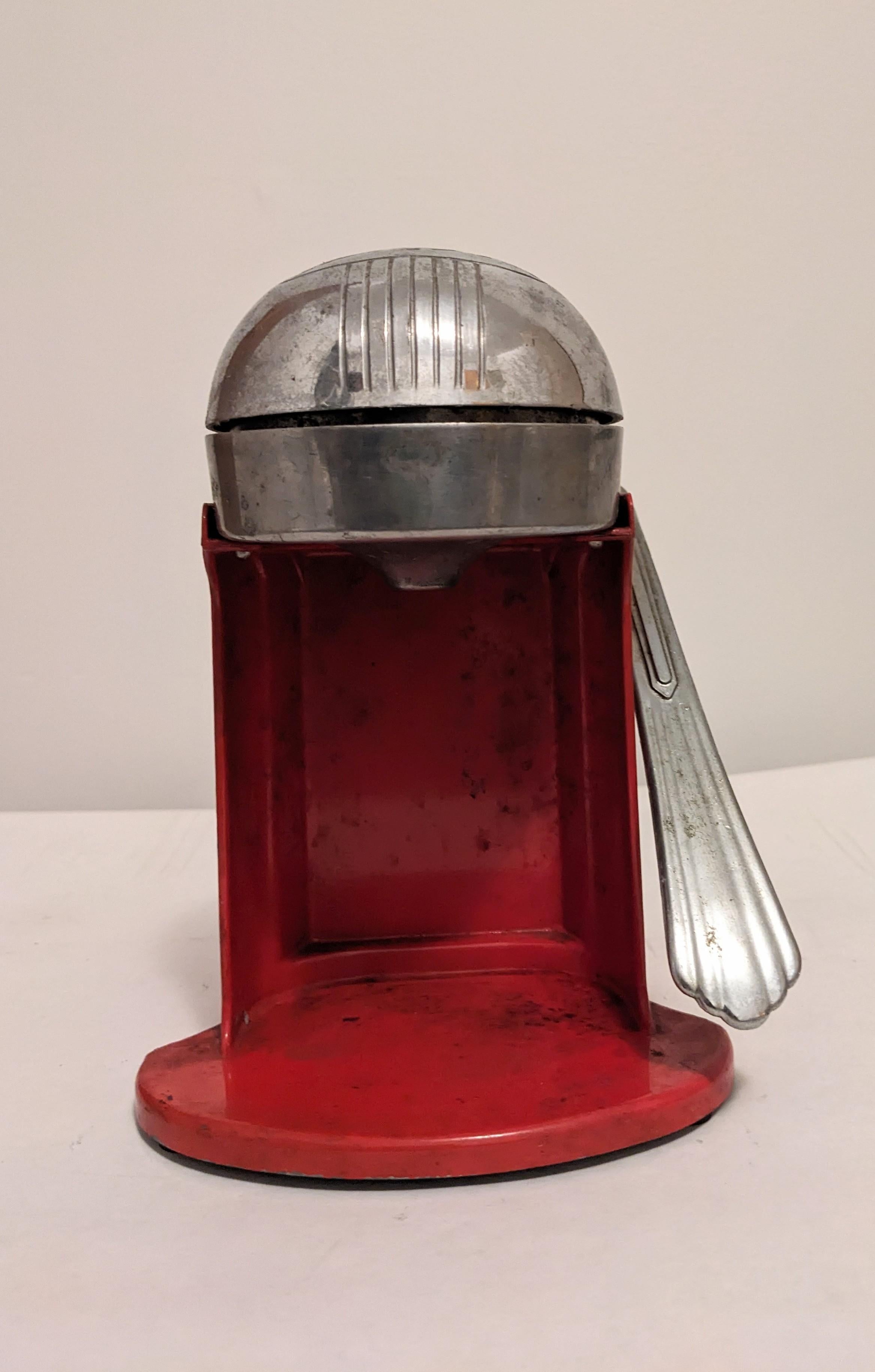 Exprimidor esmaltado Art Decó de la década de 1940. Diseño envejecido a máquina con base de esmalte rojo. Se coloca fruta en la cavidad y se tira de la palanca hacia abajo para exprimir el zumo. Juice-O-Mat. Años 40, EE.UU. 
8