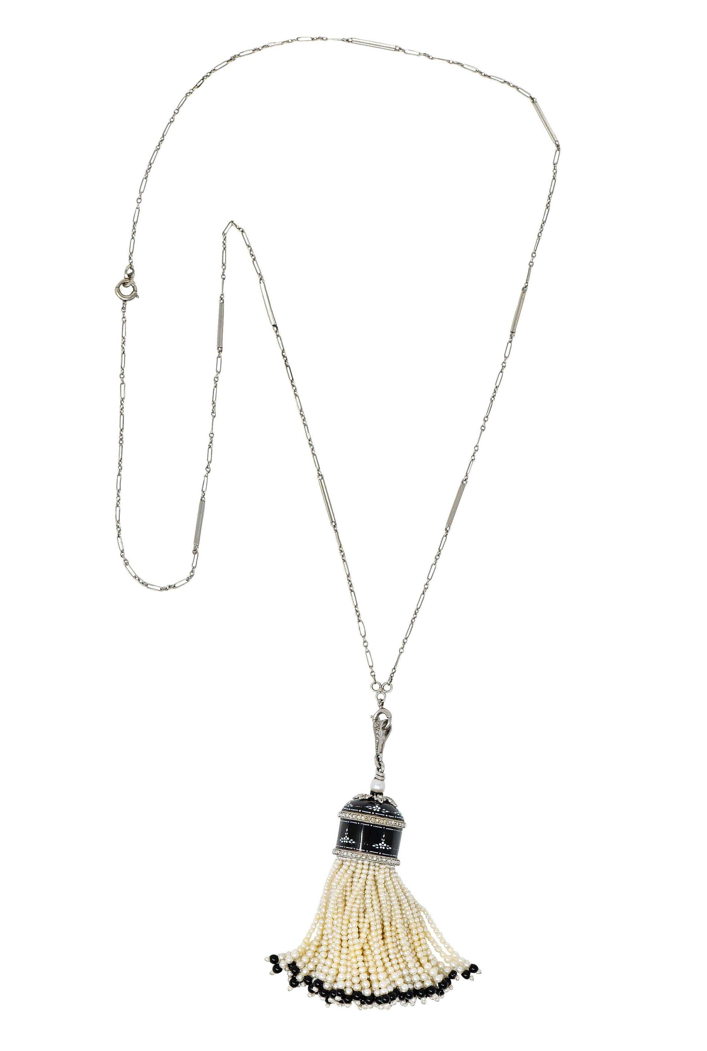 Centering a tassel pendant glossed with black enamel accented by hand-painted floral details

With milgrain platinum details as two bands, a floral motif, and bale - all accented by rose cut diamonds - one missing

Topped by a bright white 4.2 mm