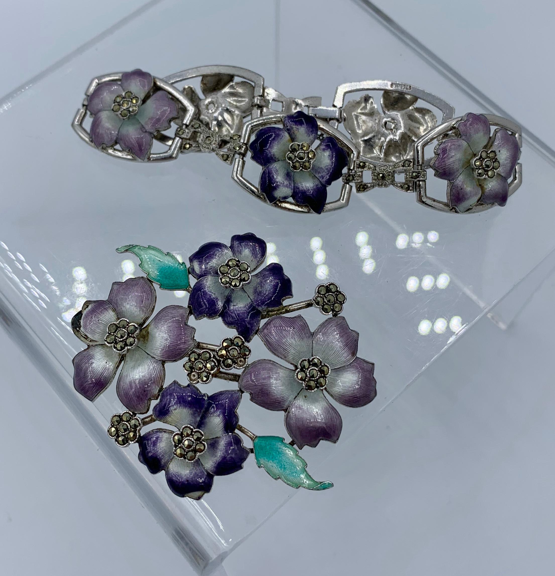 This is a very rare Art Nouveau - Art Deco violet pansy flower parure with a matching bracelet and brooch with exquisite flowers decorated with varied hues of purple enamel, with green leaves and marcasite set centers in Sterling Silver.  The