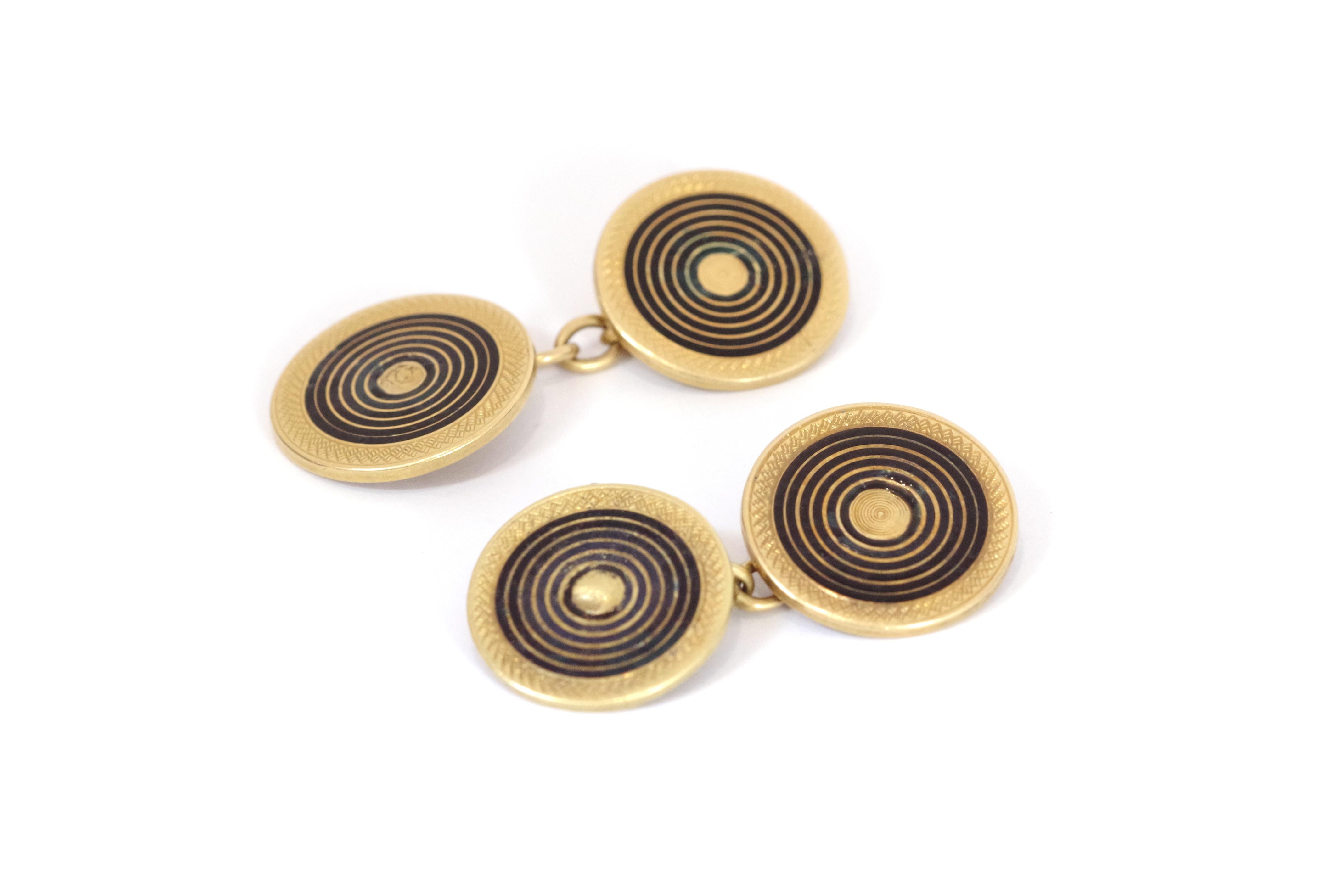 Art Deco enameld cufflinks are made of 18 karat yellow gold and feature a circular design with black enamel concentric circles on a gold background, creating a target-like pattern. The edges of the gold circles are adorned with notched borders.
