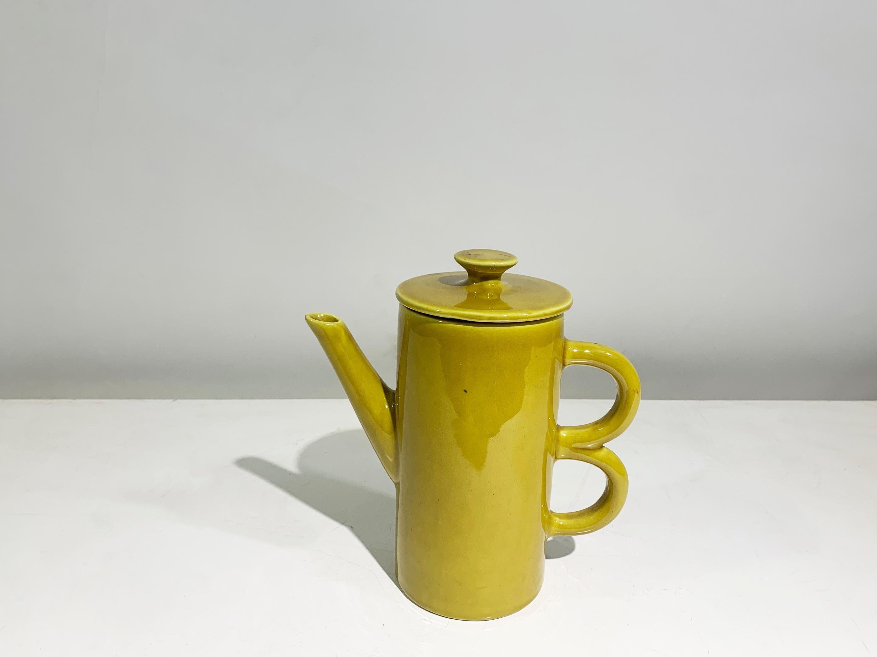 Exemple rare et éclatant de la céramique italienne du début du XXe siècle, cette théière Art déco date d'environ 1930. 
Rendue dans un glaçage jaune moutarde audacieux, la pièce incarne l'optimisme et l'élégance sculpturale de l'époque. Son corps