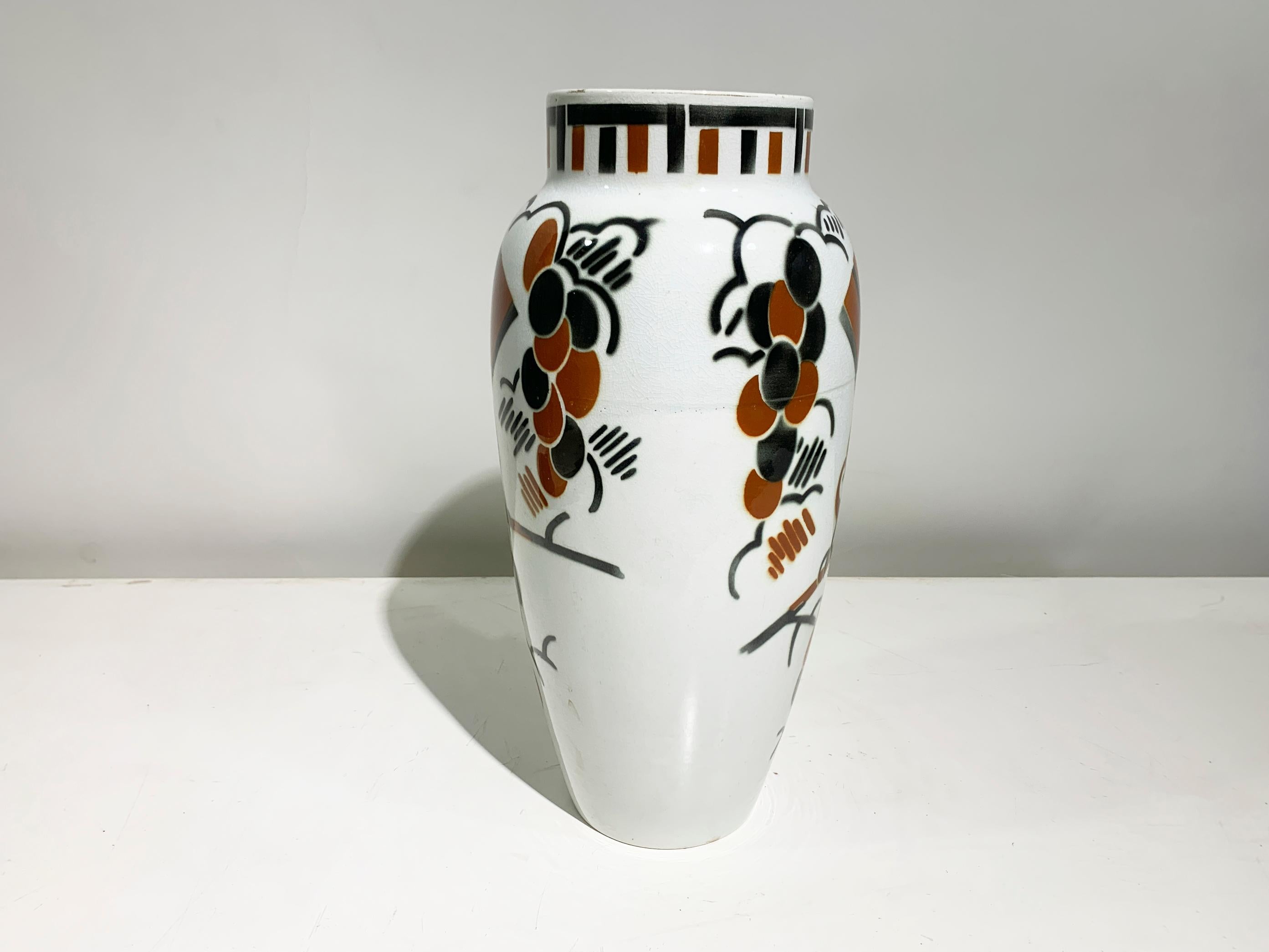 Questo sorprendente vaso Art Déco, firmato da Keller & Guérin Lunéville, presenta una forma a balaustro con un colletto rialzato. Il design mostra un elegante gioco di uccelli e rami stilizzati, illustrati in un ricco smalto marrone e nero su uno