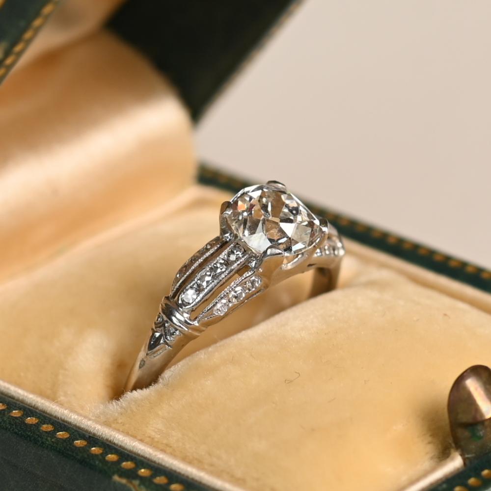Este exquisito Anillo de Compromiso Art Decó, realizado a mano en platino hacia 1930, muestra la elegancia distintiva de la época. En su centro hay un impresionante diamante de talla europea antigua, con un peso aproximado de 1,00 quilates, color I