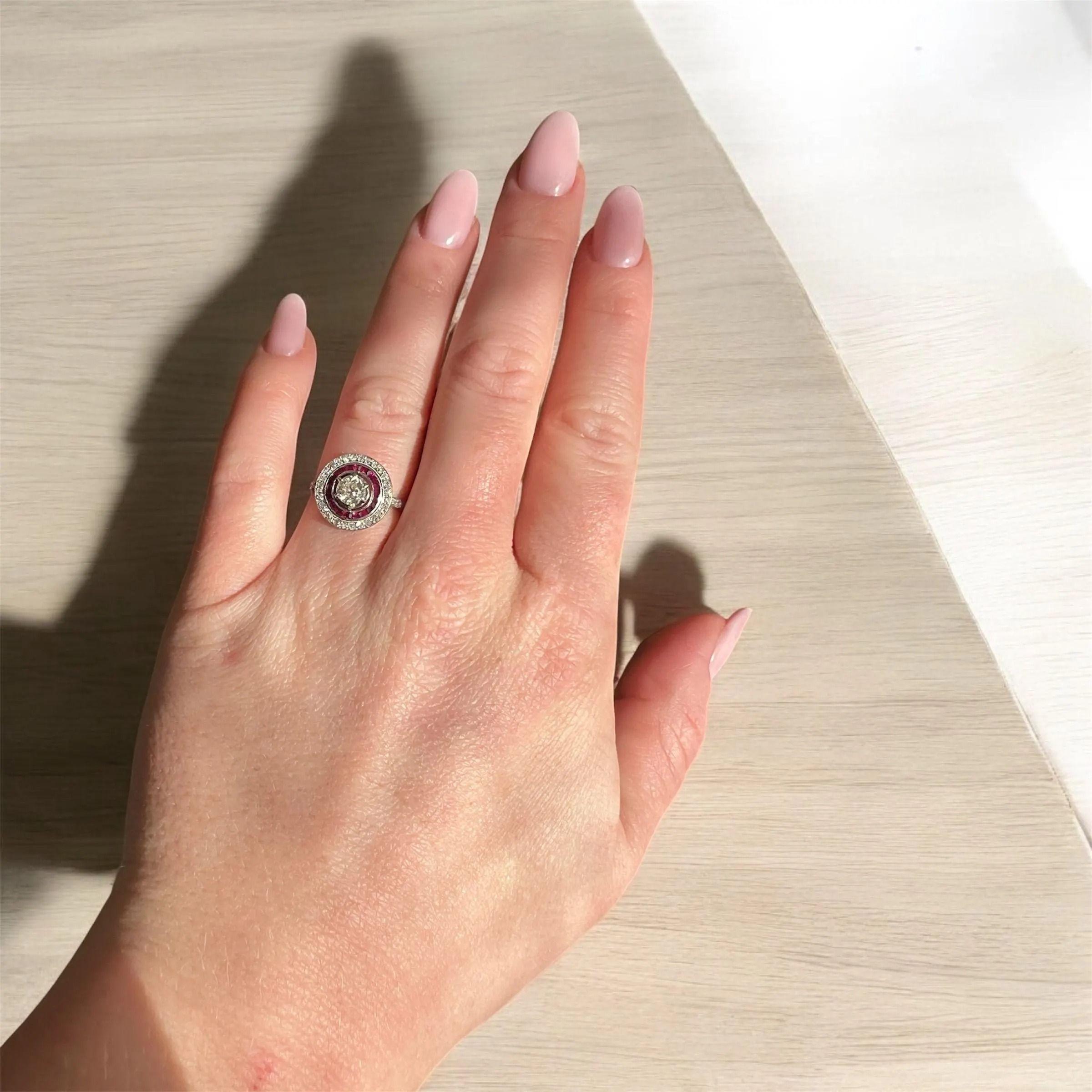 Este anillo de compromiso Art Decó, de hacia 1930, es un notable ejemplo de la refinada artesanía de la época. Realizado en platino, presenta un diamante central talla antigua de aproximadamente 0,50 quilates, engastado dentro de un llamativo halo