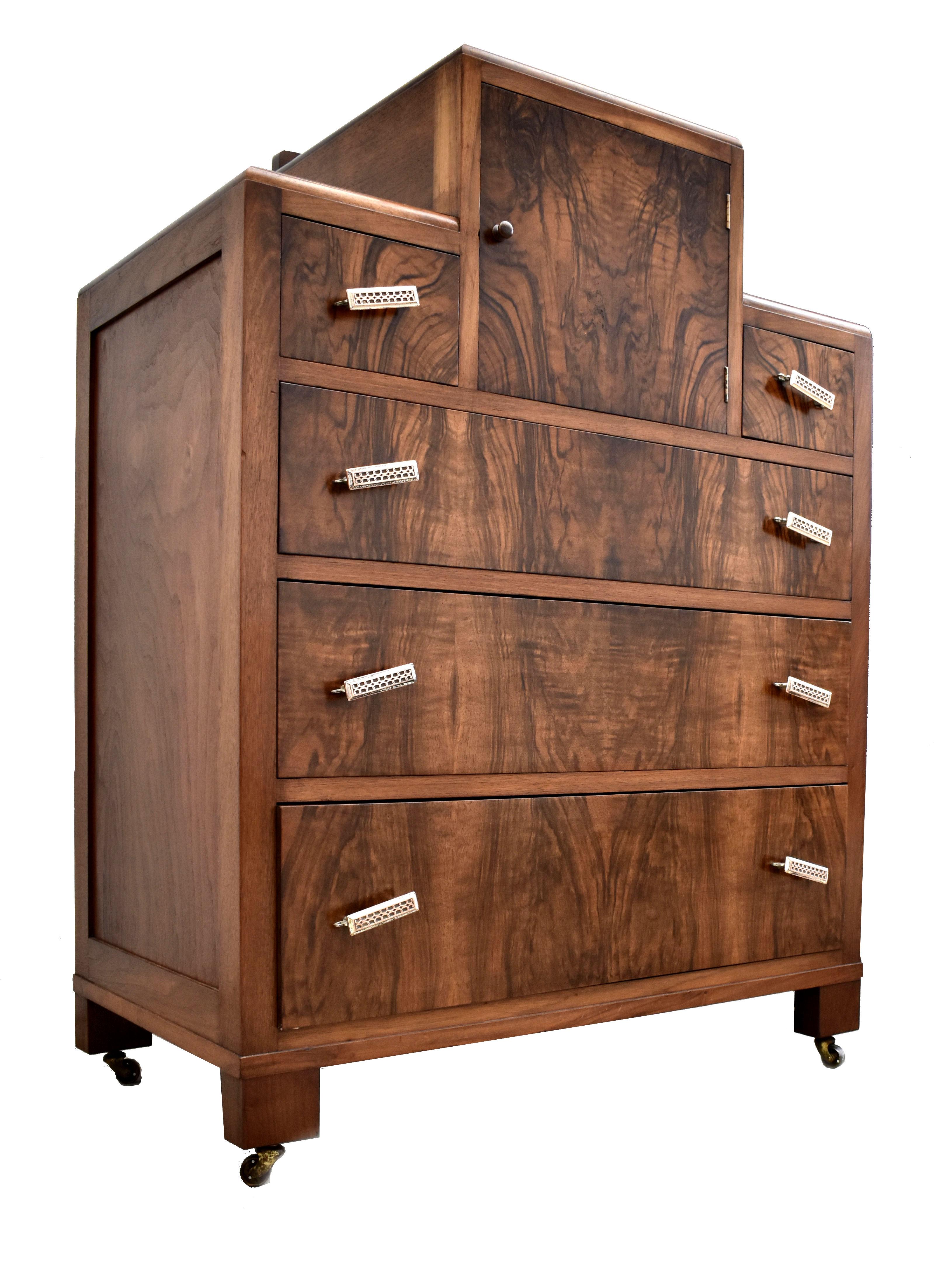 Very stylish Art Deco walnut chest of five drawers originating from England and dating to the 1930's. It has stunning walnut veneers with original Art Deco handles in chromed brass. Book matched veneers sync down the front of the drawers with