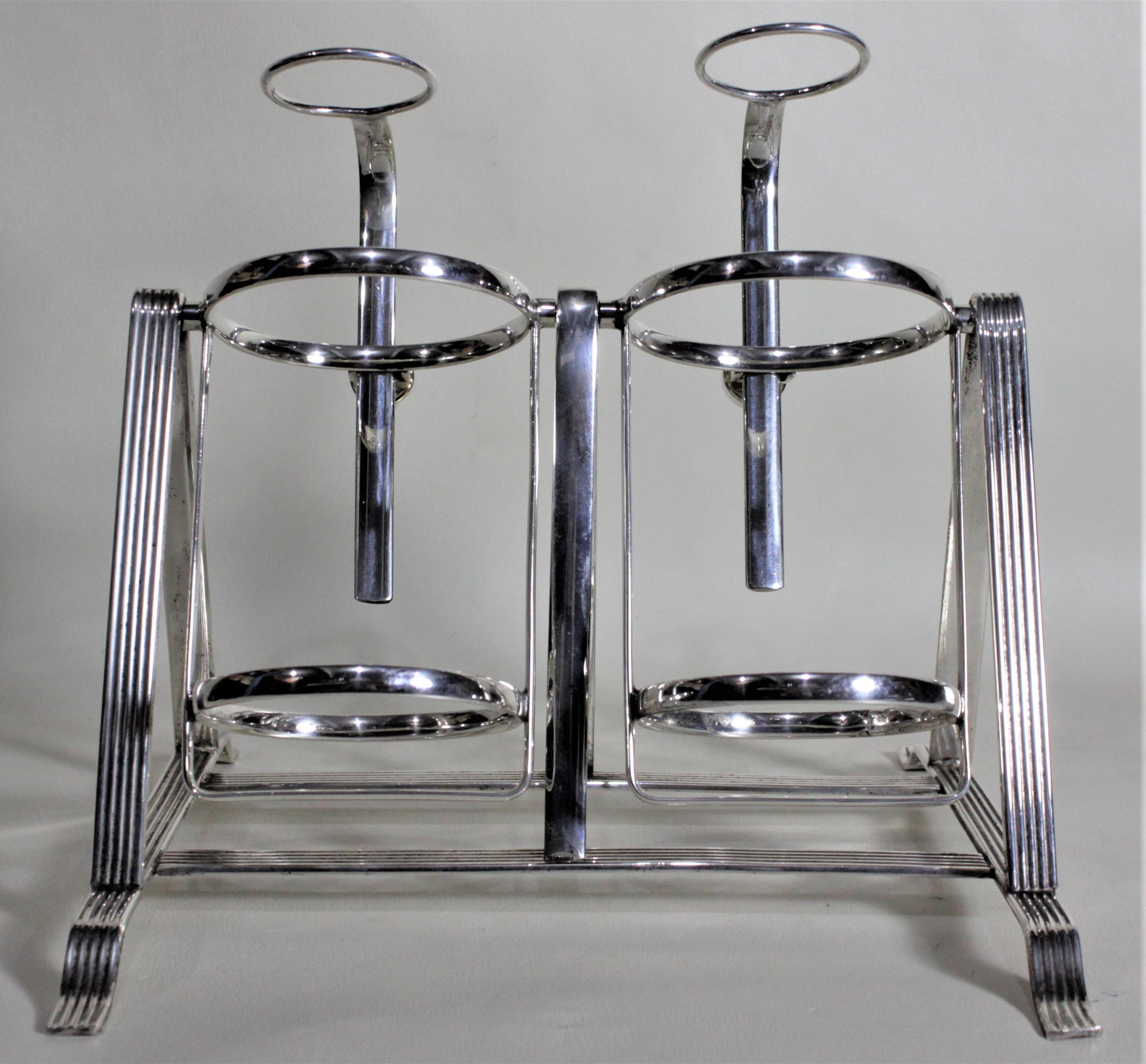 This silver plated decanter stand was made in Birmingham England by the Arnold E. Williams silversmiths in circa 1929 in the period Art Deco style. The stand holds two decanters or bottles of varying sizes and pivots so the contents can be poured by