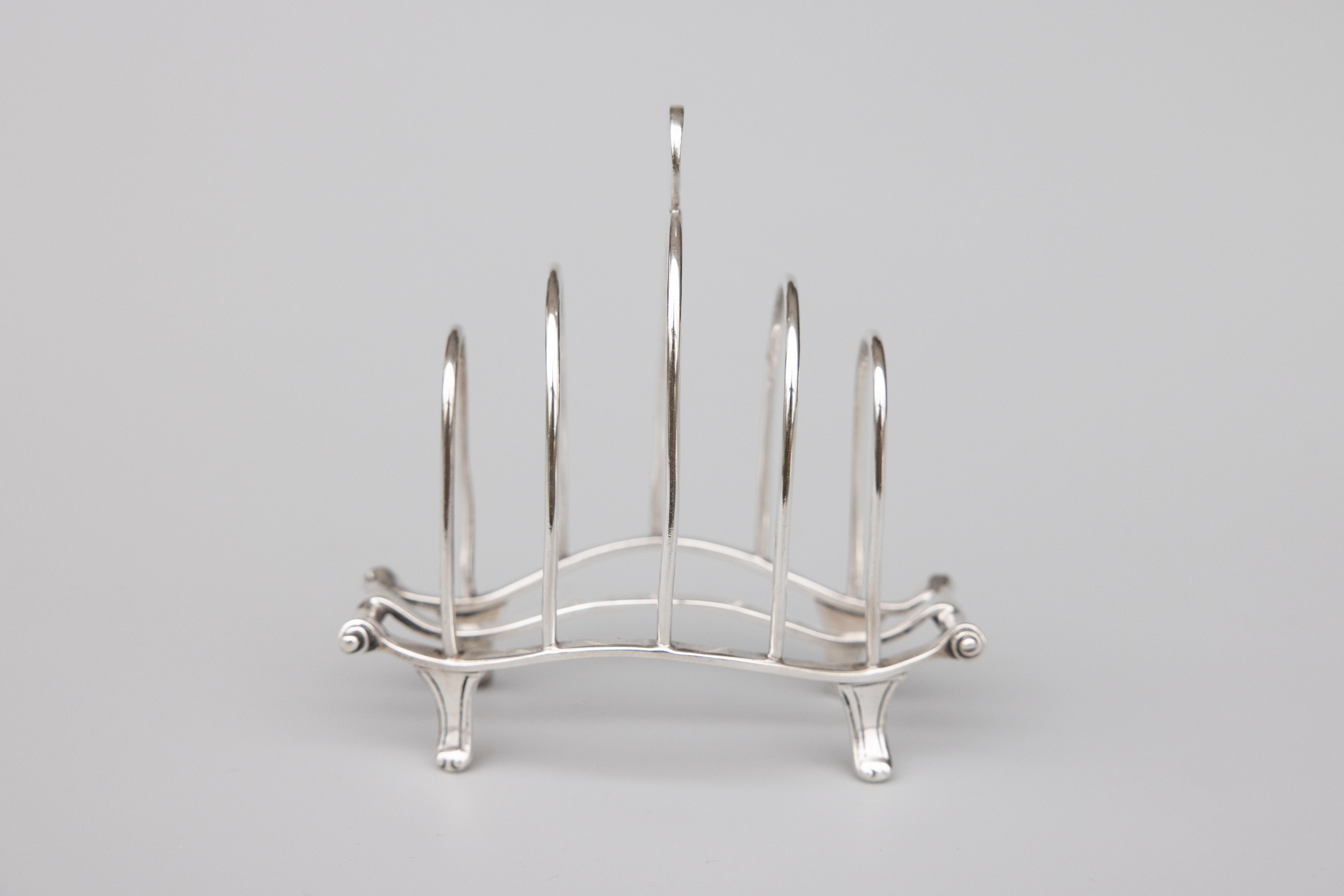 A superb antique English sterling silver four slice toast rack made by William Comyns & Sons Ltd in London, dated 1924. Hallmarks on reverse. This stunning toast rack has a lovely Art Deco design, ornate feet, and decorative finial. It would be