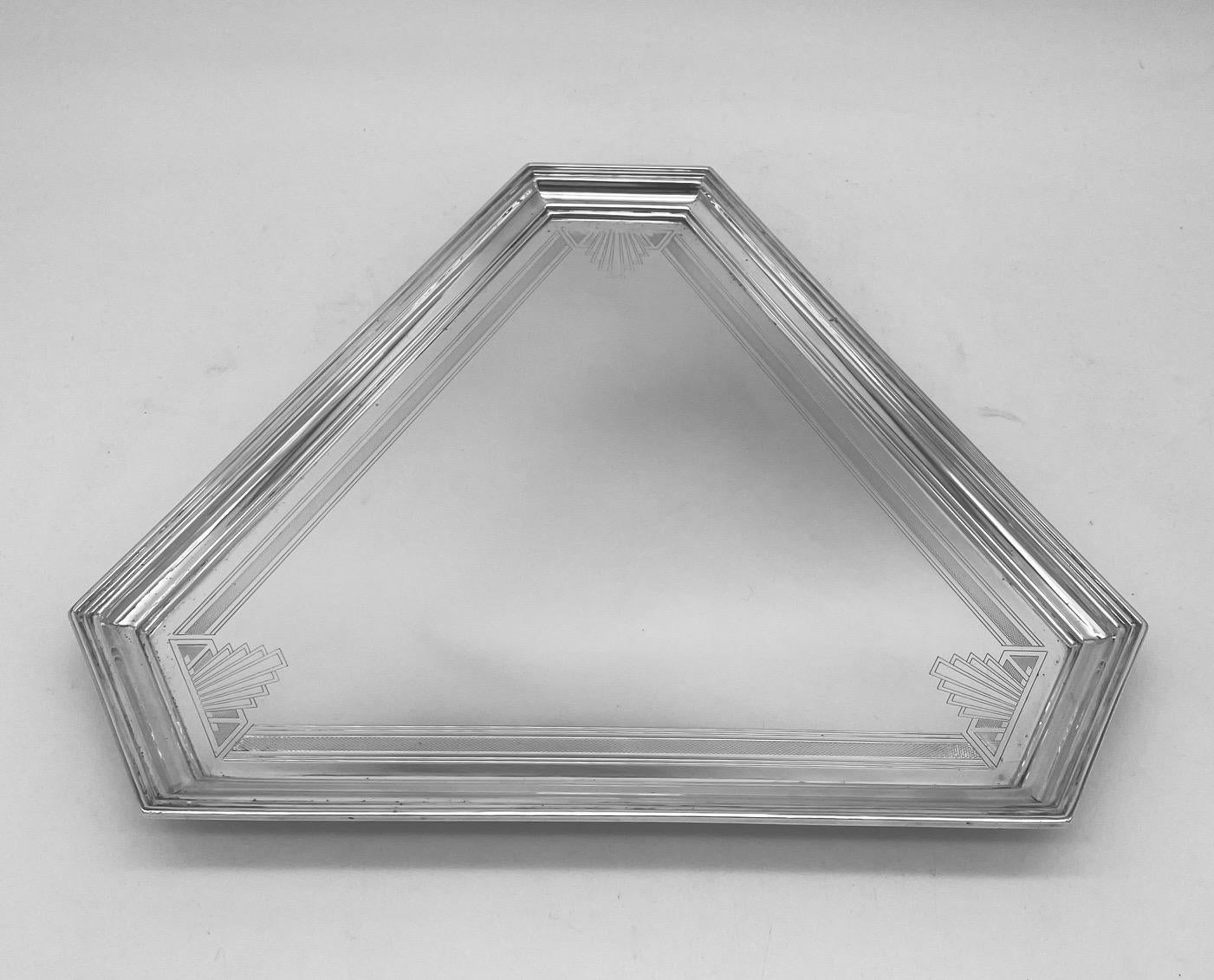 This is a lovely Art Deco sterling silver tray or salver, of canted-corner triangular form and with geometric engraving. The salver, which stands on three feet, is perfect for serving drinks or as a display piece in a 1930s setting. 
It is