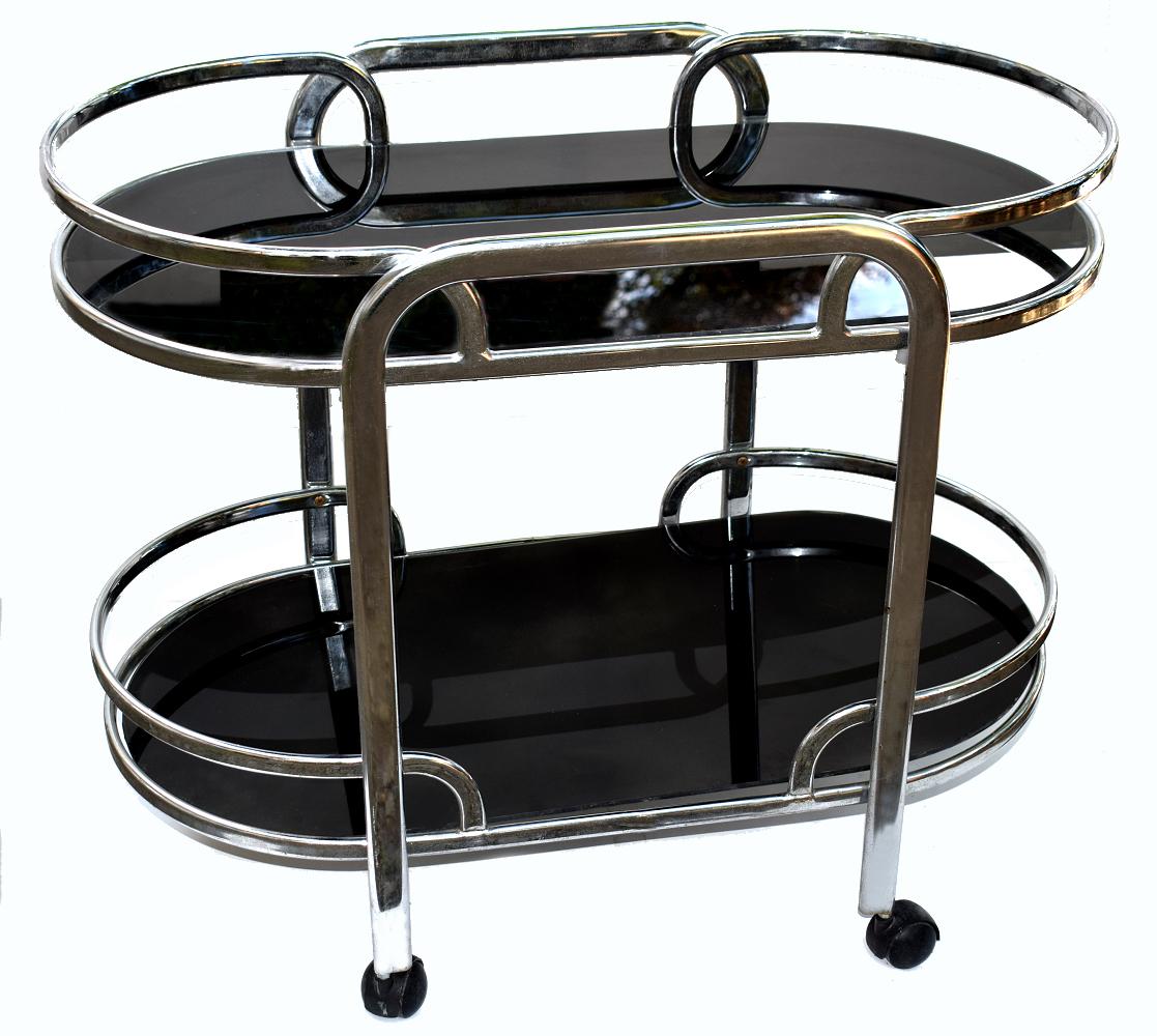 Stylish English 1930s Art Deco two-tier chrome and black glass drinks hostess trolley bar cart. This design is a little more unusual in shape than you normally find and is a lot more substantial in weight, quality and is very sturdy. If glam is your