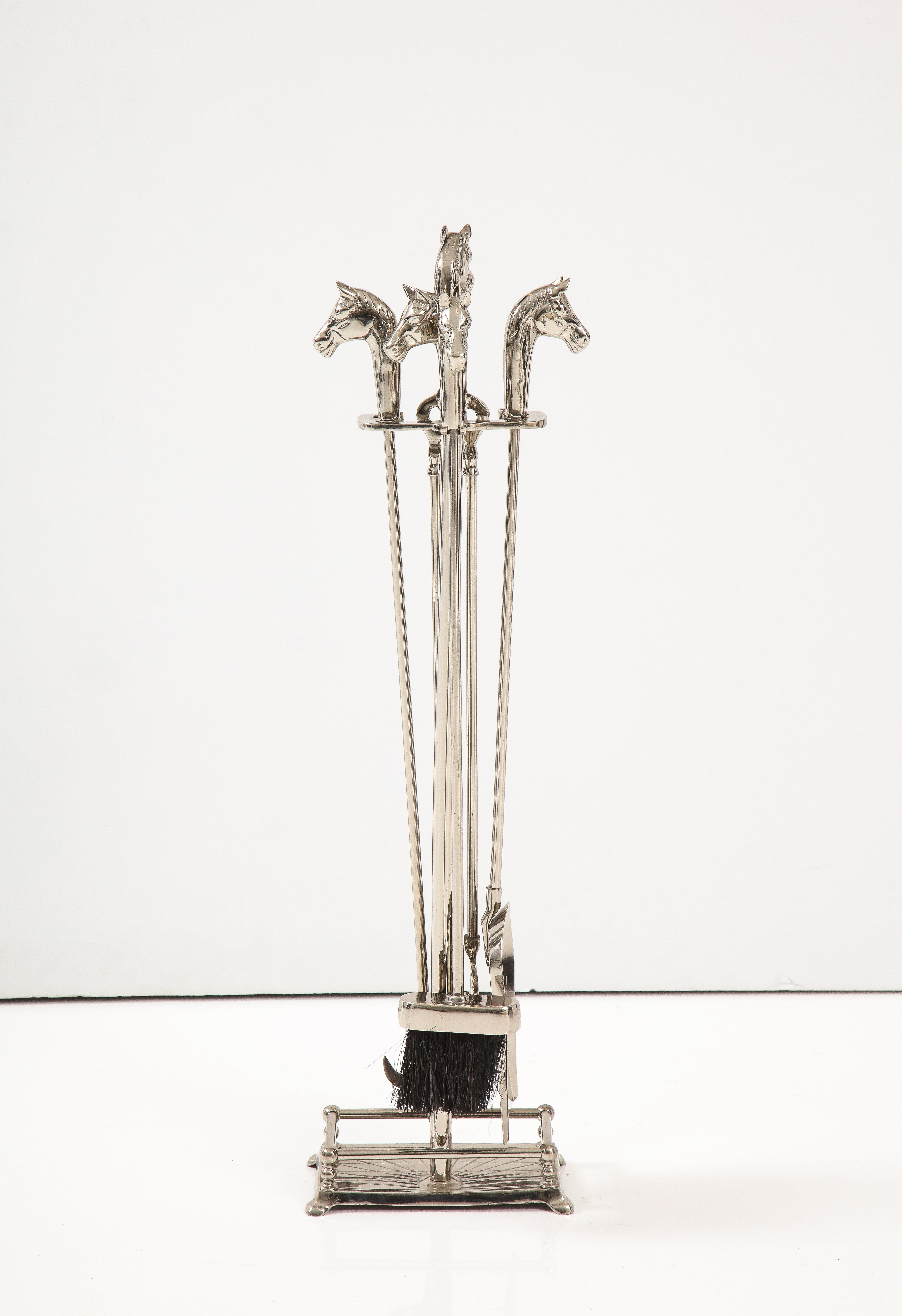 Set of polished nickel Art Deco fireplace tools with horse head handles. Set includes stand, poker, shovel, tongs and brush.