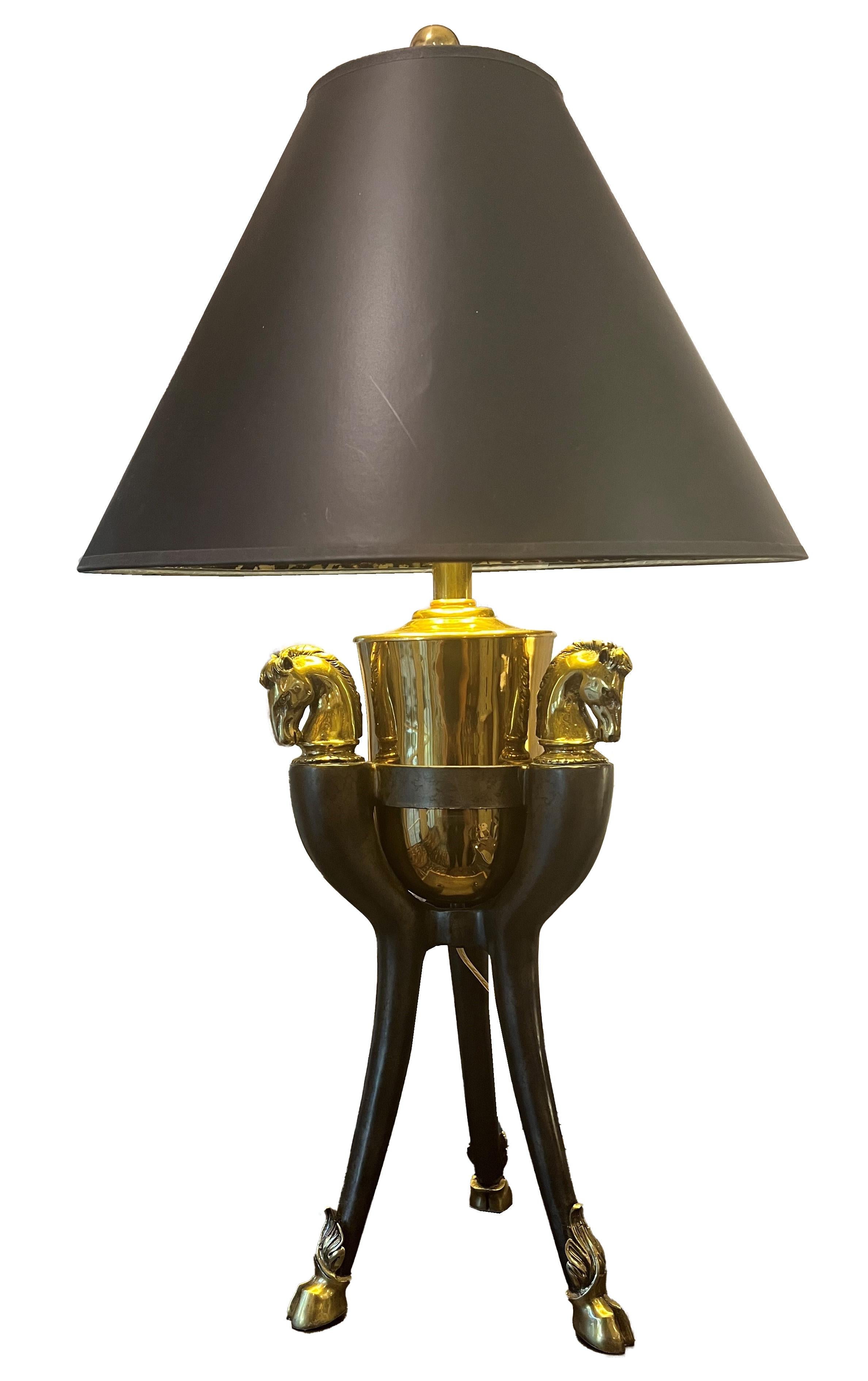 Immerse your space in the allure of the Art Deco era with this unique Equestrian Table Lamp, a striking fusion of sophistication and equine-inspired design. The brass horse heads and hoofs motifs form an exquisite base. Topped with a black paper