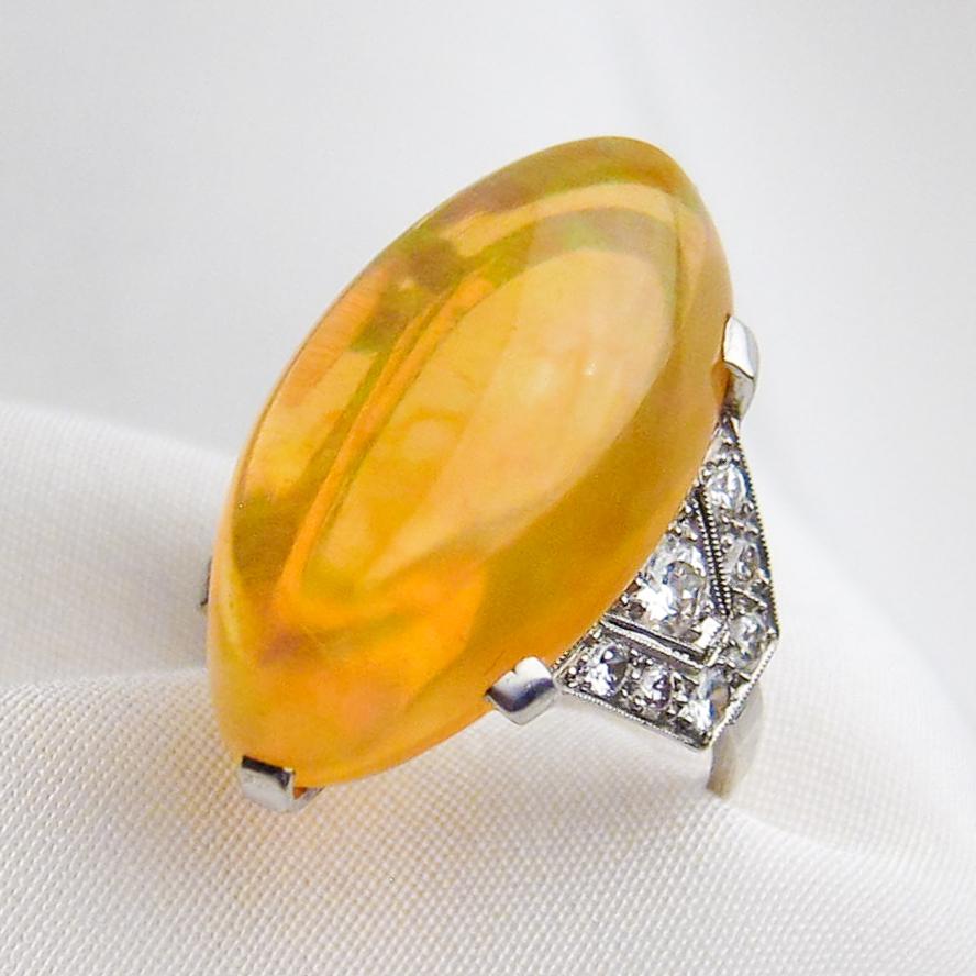 Circa 1930. This fantastic Art Deco Era ring features an incredible marquise-shaped orange Ethiopian opal cabochon weighing 14.75 carats and set in a six-prong platinum head. The shoulders of the setting are each adorned with seven bead-set round