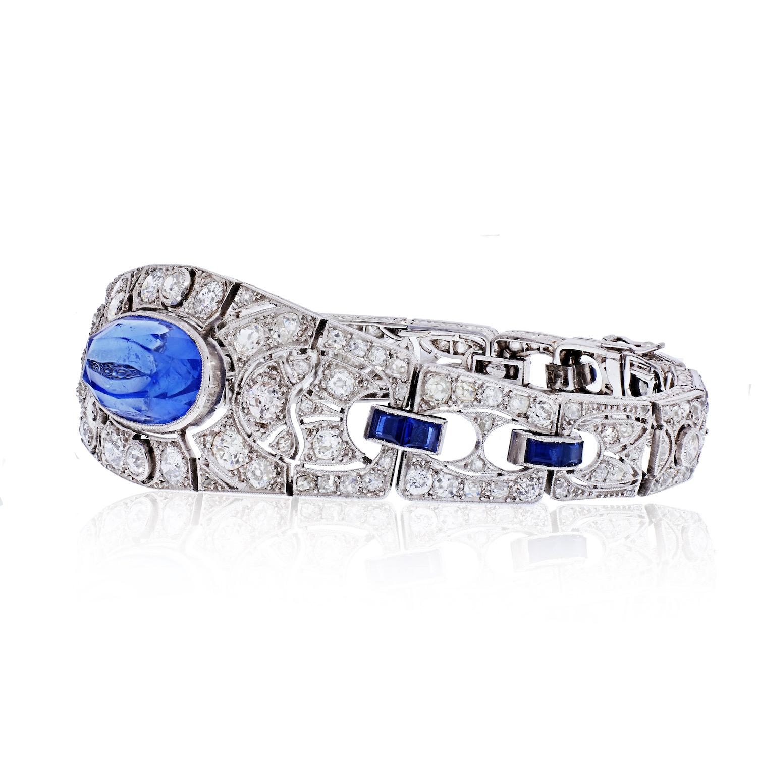 Centering an over 20 Carat Ceylon (Sri Lanka) Cornflower Blue Sapphire, accented by 14 Princess-Cut Blue Sapphires and 166 Old-European Cut Diamonds, and set in a 18K Gold/Platinum blend, this classic Art Deco bracelet is designed by famed Swiss