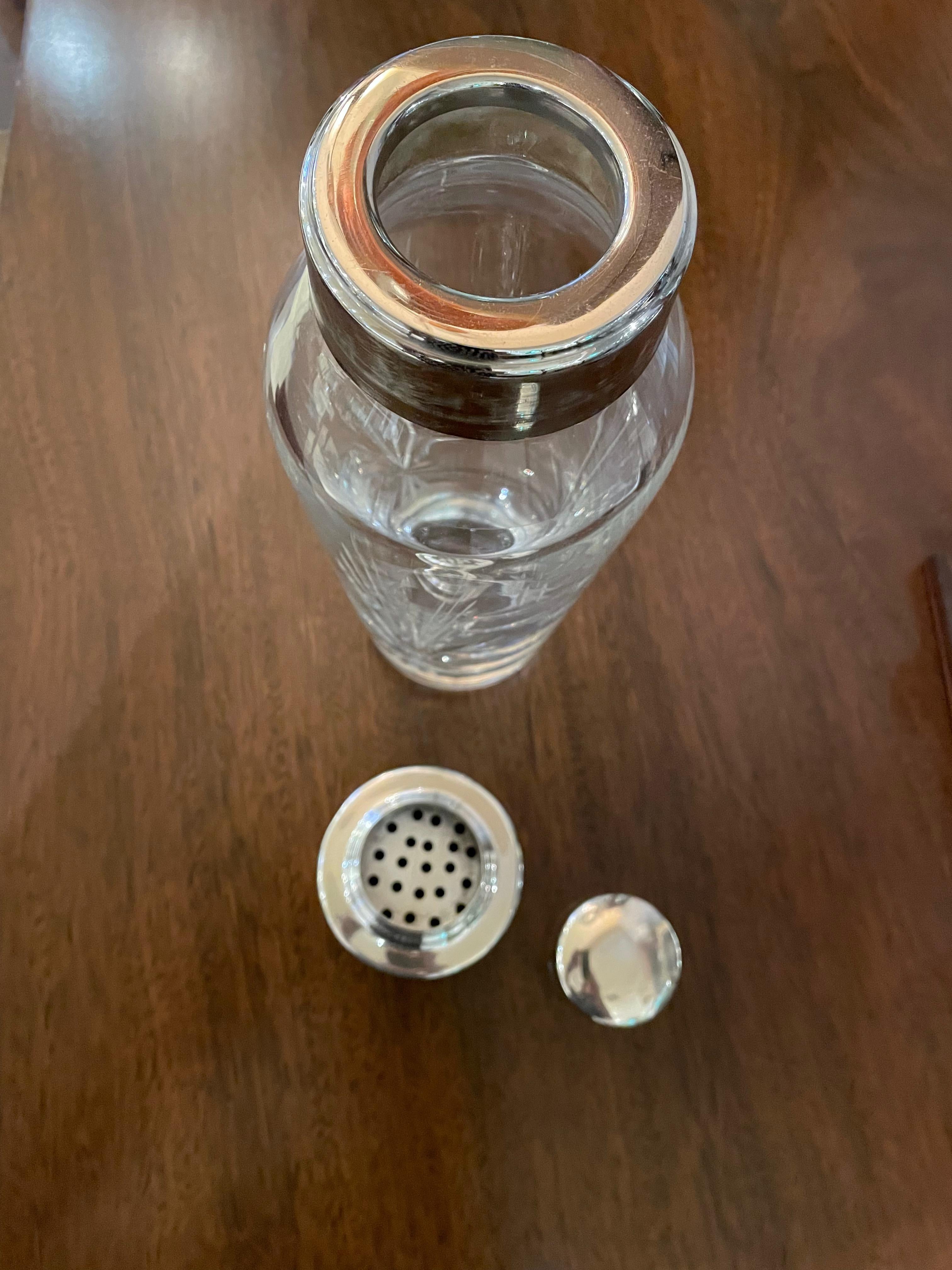 A cut crystal cocktail shaker with deep engraving done in the Czech tradition with a silver plated rim, strainer, and top. The design is a dynamic starburst and cross-hatch pattern that refracts the light and will look perfect on your bar display