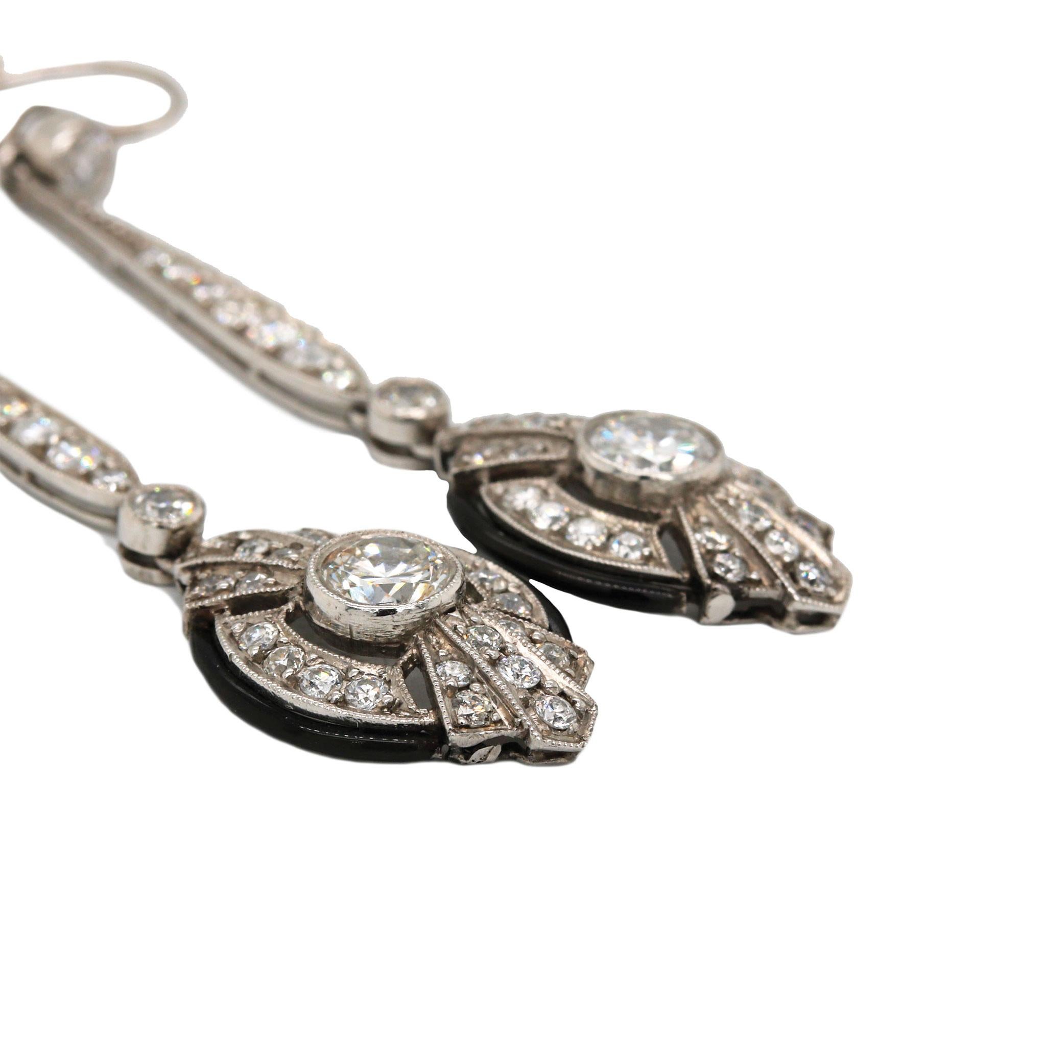 A pair of Art Deco era platinum diamond dangle earrings, with a combination of Old European Cut and brilliant cut diamond accents. These collectible earrings are bezel set with two center round brilliant cuts that total 0.77ctw, graded G-H in color,