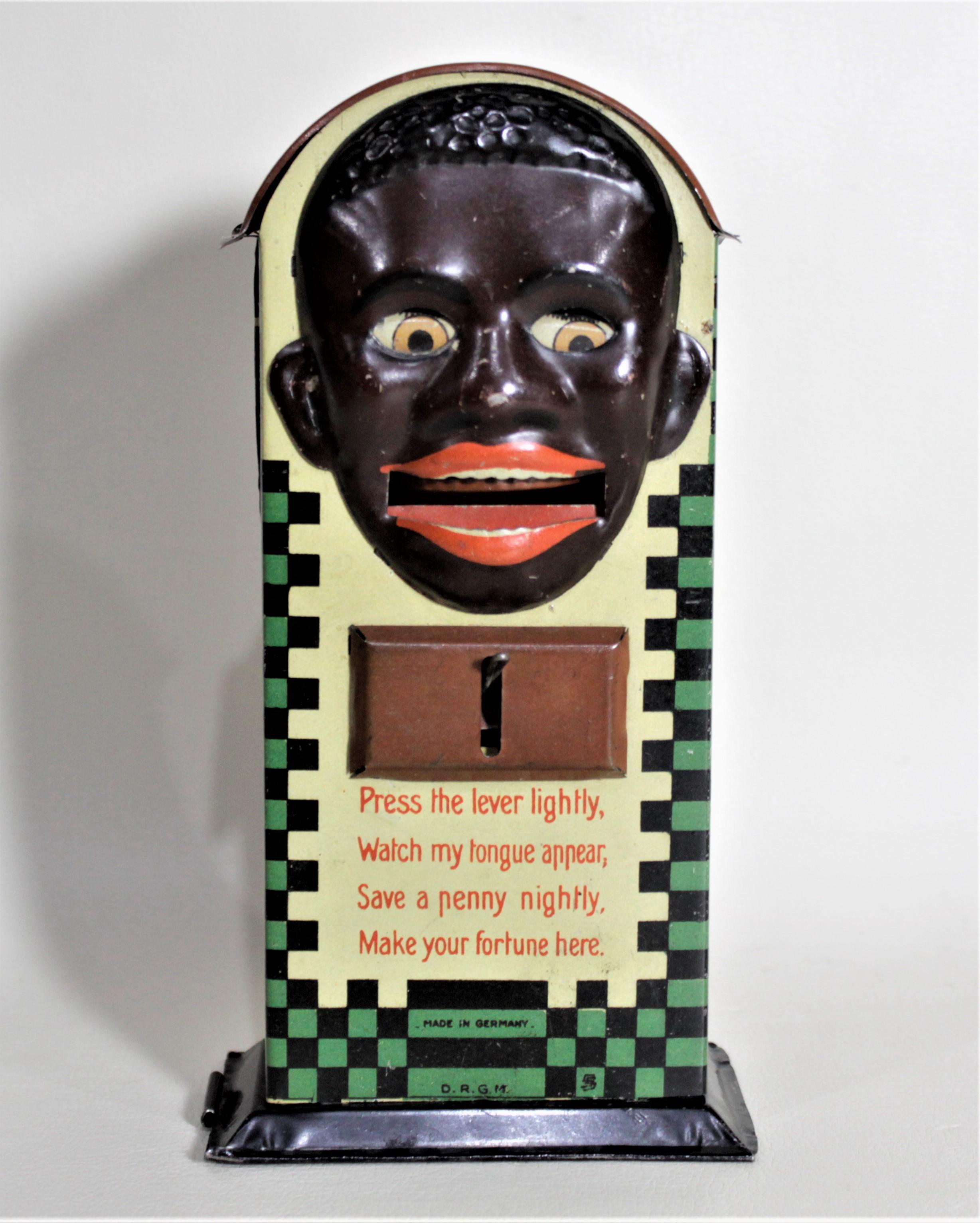 This lithographed tin coin bank was produced in Germany in circa 1935 in the period Art Deco style. The bank is shaped like a coin box with a man's face on the front. When the lever is pulled, the man's eyes close and his tongue appears which a coin