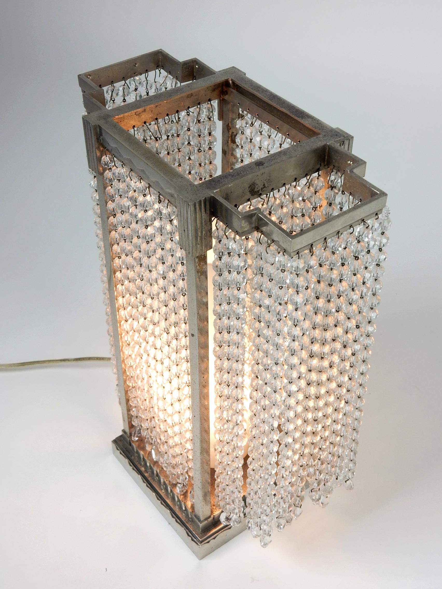 Incredible 1930s nickel silver plated and glass bead tabletop illuminare.
Stylist Art Deco skyscraper design frame. Single bulb socket with milk glass chimney.
Only manufacturer or design mark is 