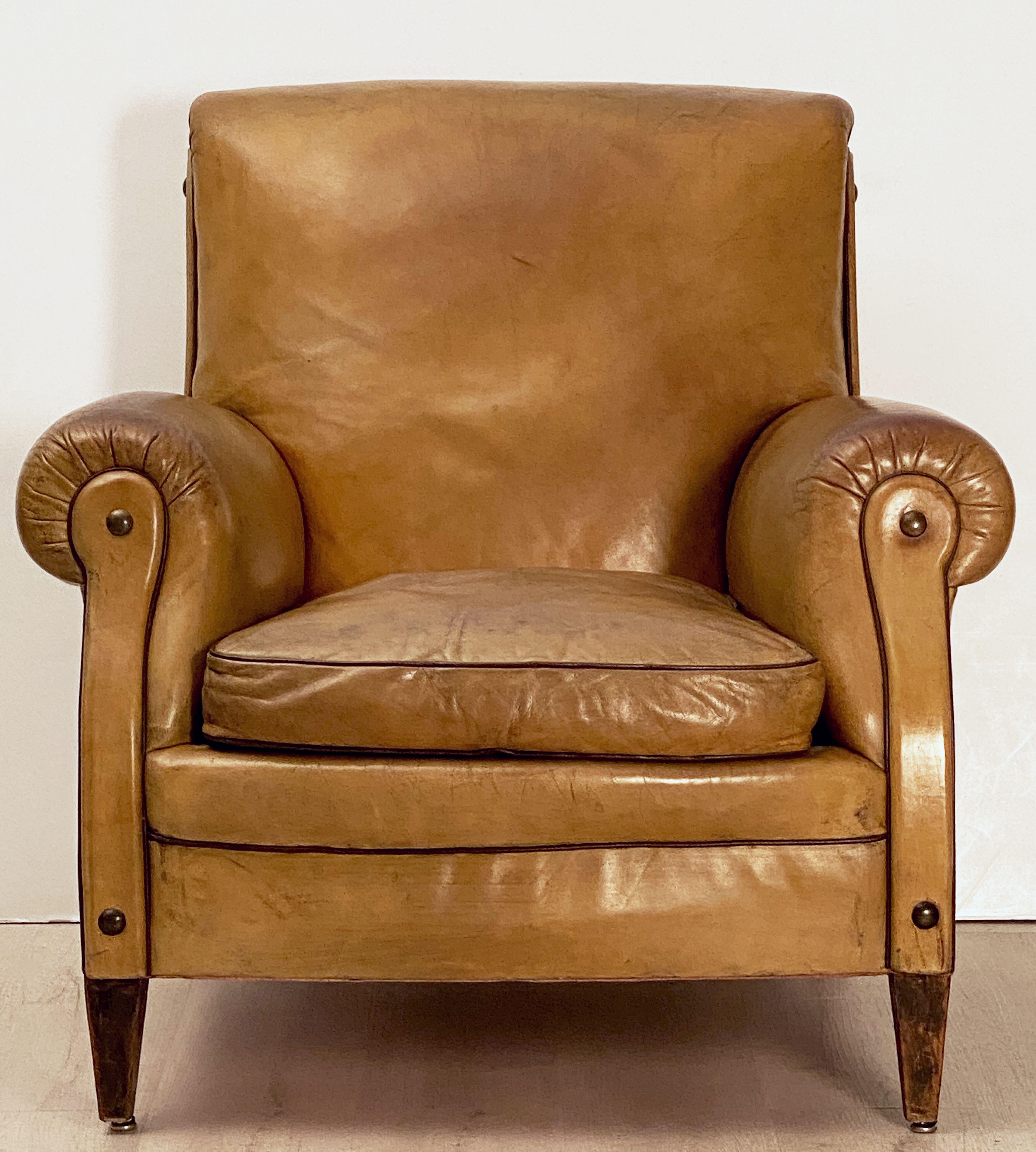 A handsome vintage Dutch leather upholstered club or lounge chair from the Art Deco era, featuring a comfortable back and seat with removable cushion, with stylish arms and original leather, button accents, brass nail-head trim to back, and resting