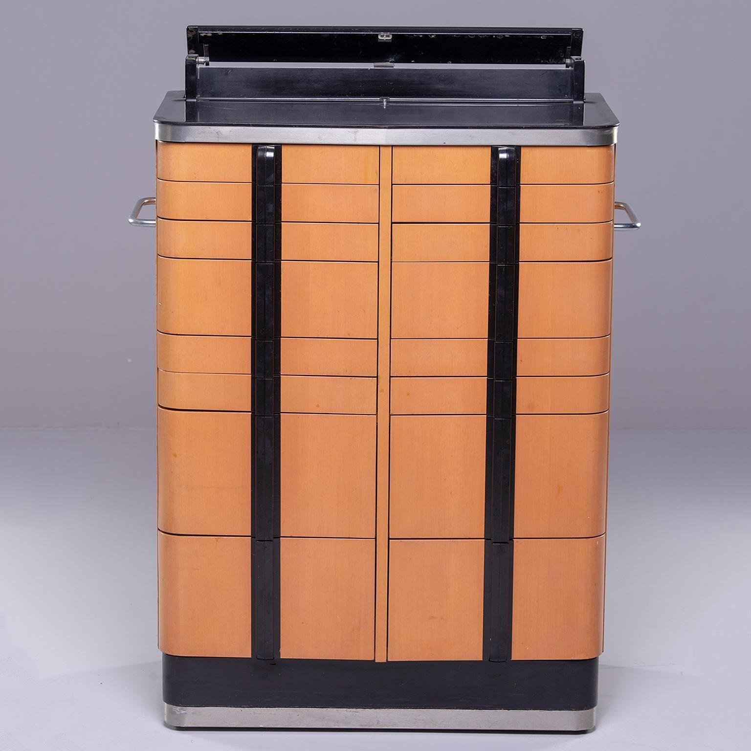 American Cabinet Company Art Deco-Stil medizinischen Schrank in Ahorn-Furnier mit schwarzen trim stammt aus den 1940er Jahren. Dieser robuste Schrank steht auf Rollen:: hat insgesamt sechzehn funktionale Schubladen und einen schwarzen Deckel:: der
