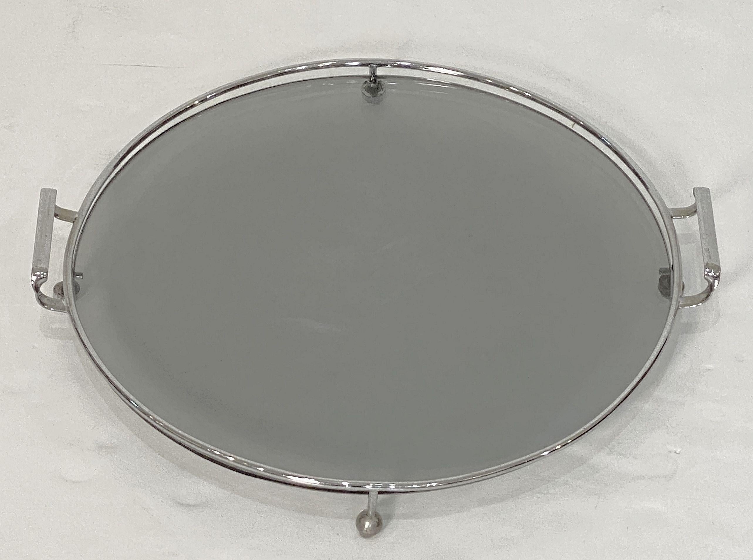 A fine English round serving tray for drinks and cocktails from the Art Deco era, featuring a chrome metal frame with two opposing handles and an inset circular plate of smoked glass, the whole on raised ball feet.