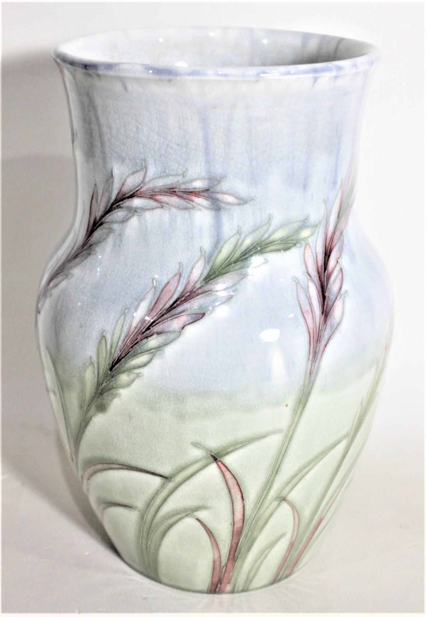 This art pottery vase was done by the Moorcroft Pottery Company of England in circa 1939 and done in their rare 'Wavy Corn' pattern. The background glaze is done in pastel blue and a pastel green representing the ground and sky, with wavy corn