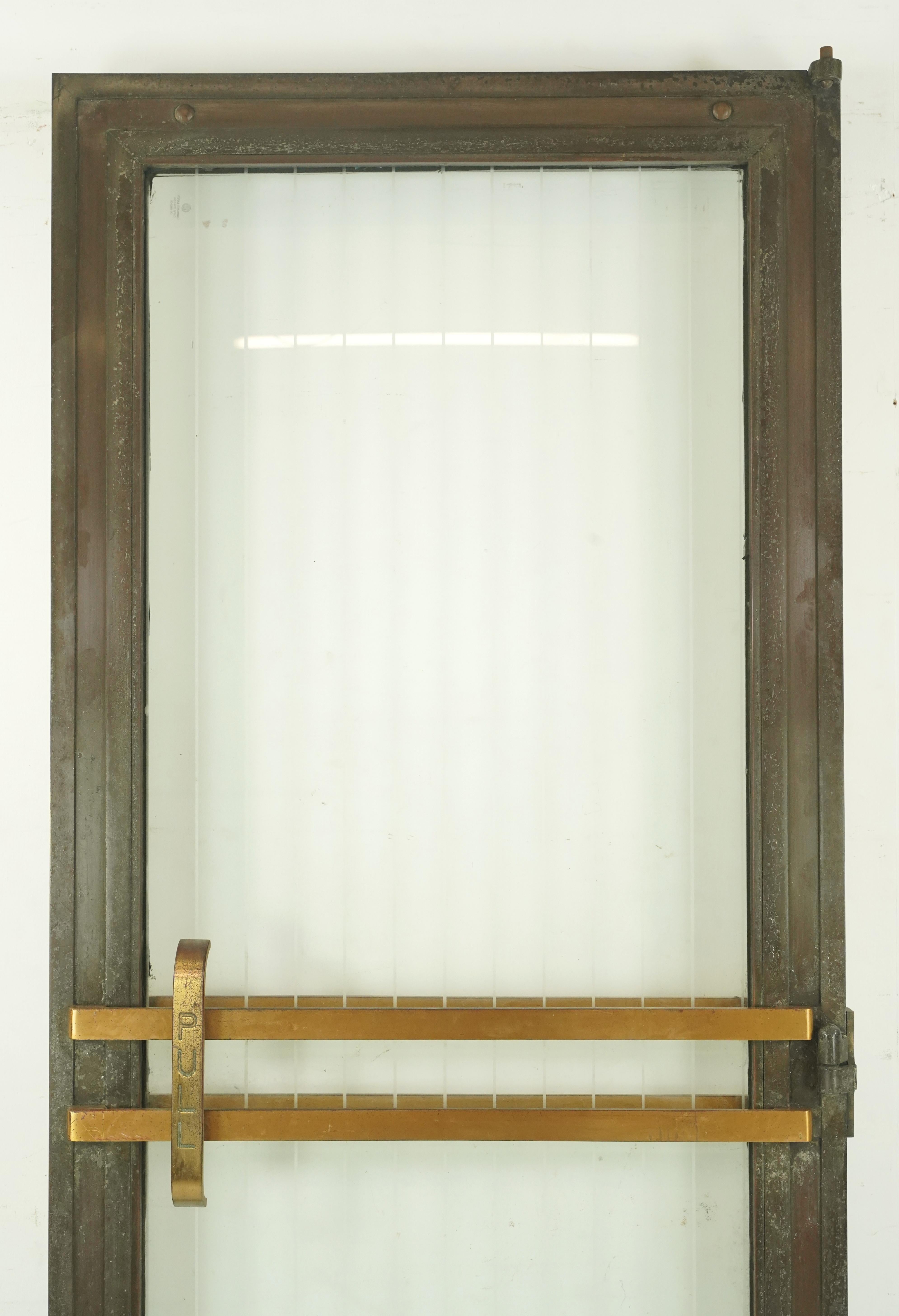 Art Deco style commercial left hand out swing bronze frame door with a full etched striped glass panel. The hinge pockets are made of steel. The pull bars are made of brass. Good condition with surface wear from prior use. Please note, this item is