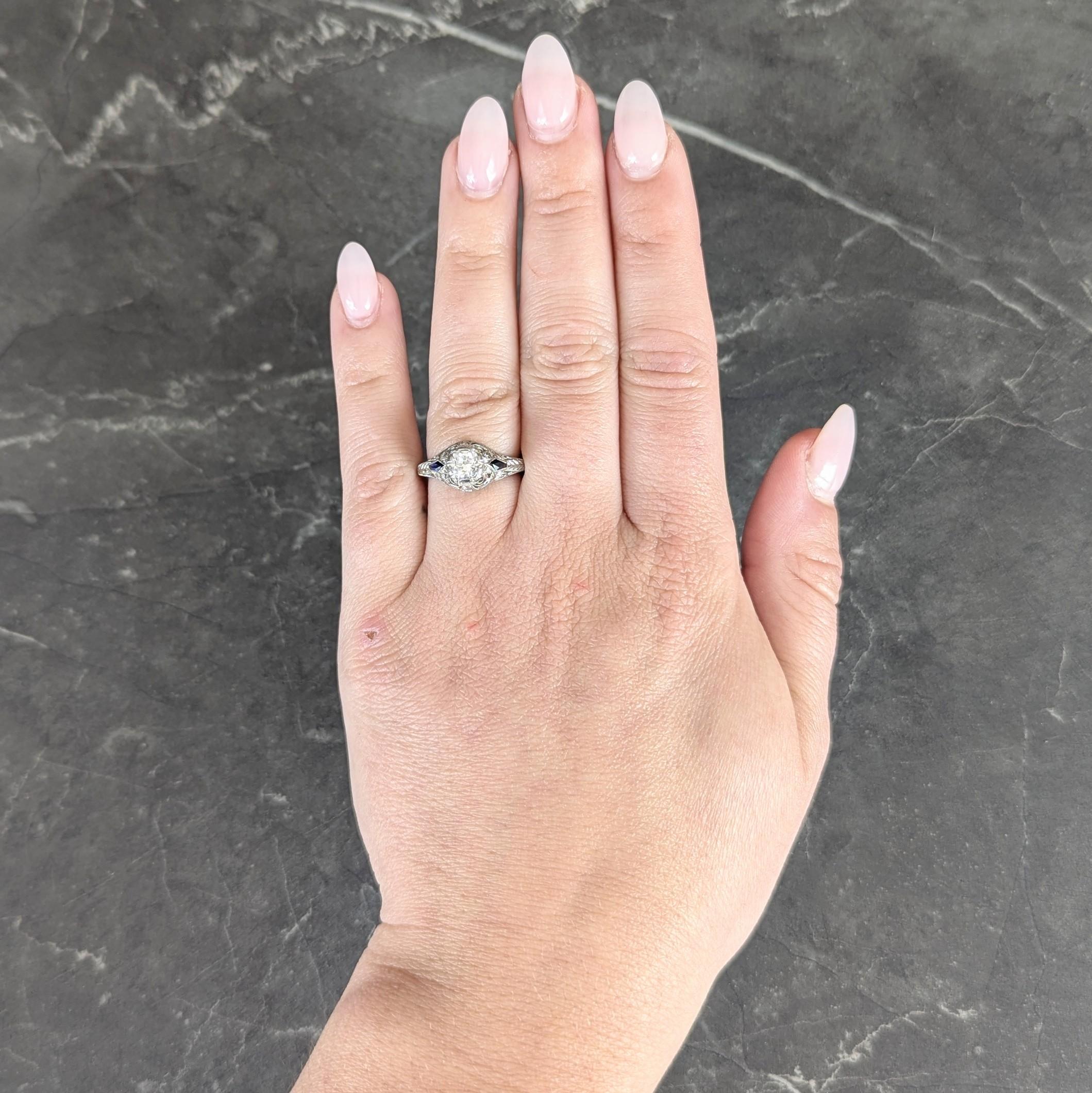 Centering an old European cut diamond weighing approximately 0.60 carat total - I color with VS2 clarity
Set with wide prongs with a pierced bombé shaped surround decorated with scrolling filigree
Accented by engraved wheat motif throughout and