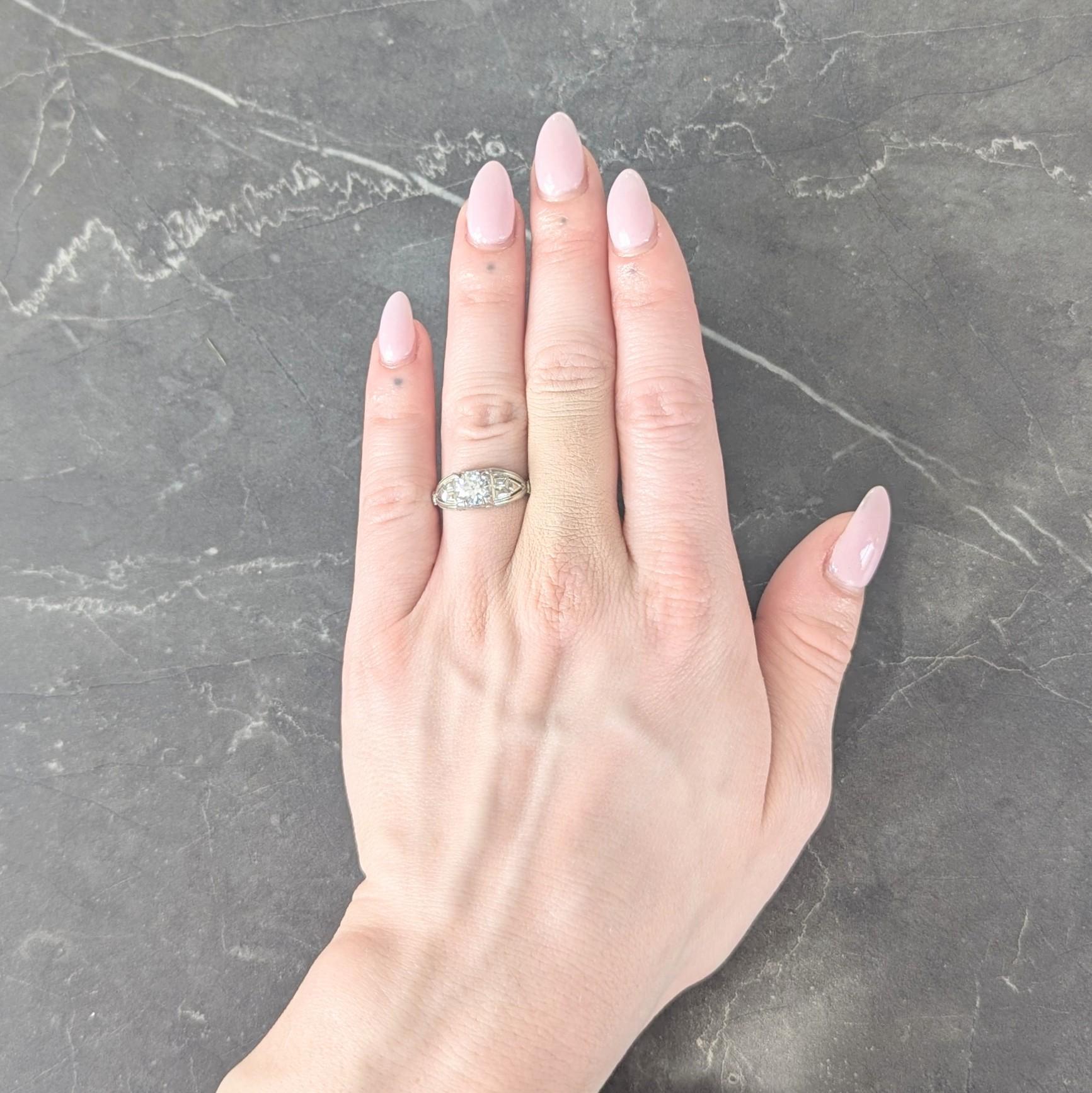 Centering an old European cut diamond weighing approximately 0.89 carat - H color with VSI clarity
Set with tri-split prongs in a square form head and flanked by pierced cathedral shoulders
Accented by grooved geometric pattern with foliate motif