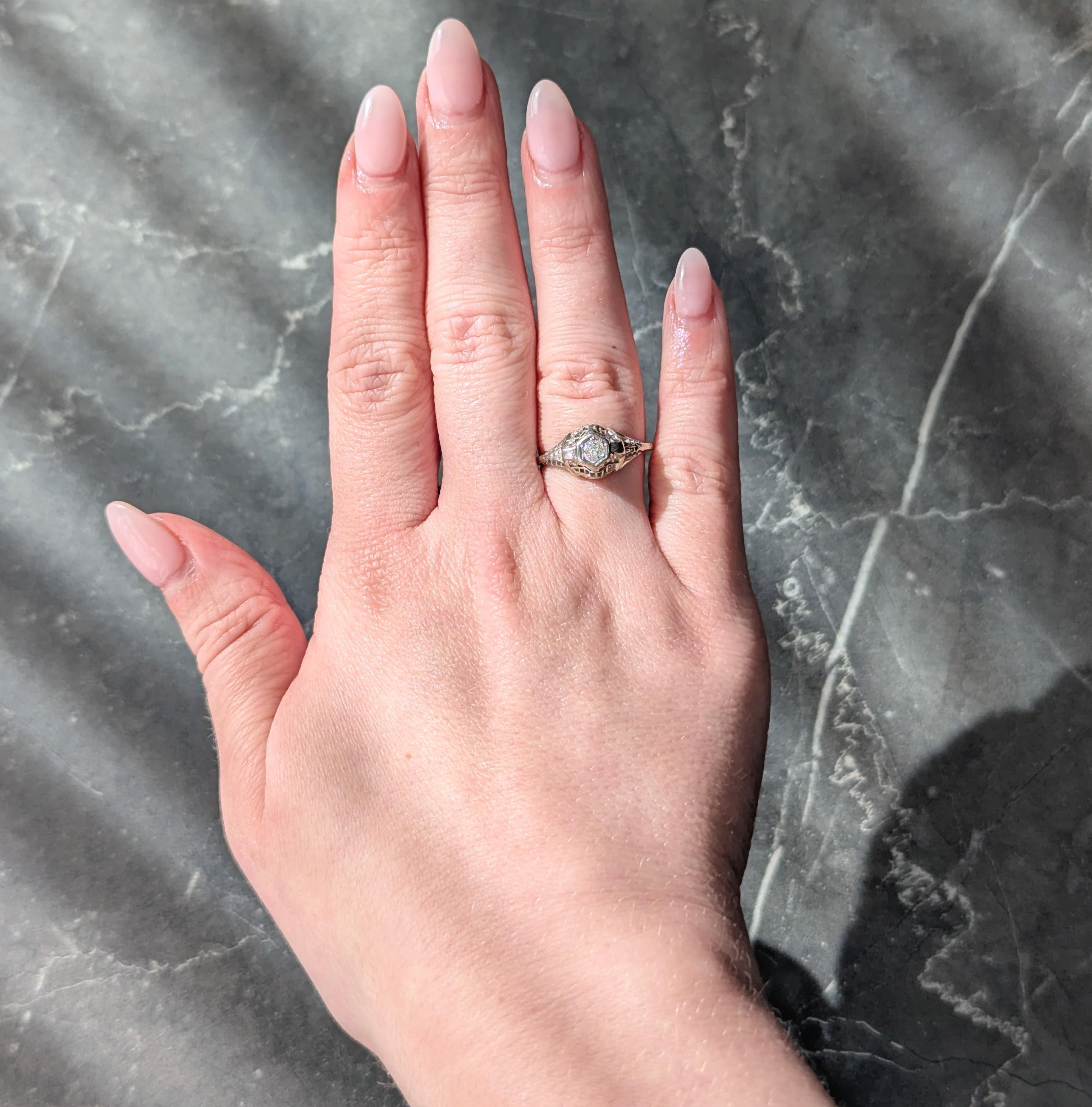 Centering an old European cut diamond weighing 0.17 carats total - I color with VS2 clarity
Bead set in hexagonal form head with a pierced bombé shaped surround
Depicting grooved scrolling volutes and palmettes in profile
Pierced with striated
