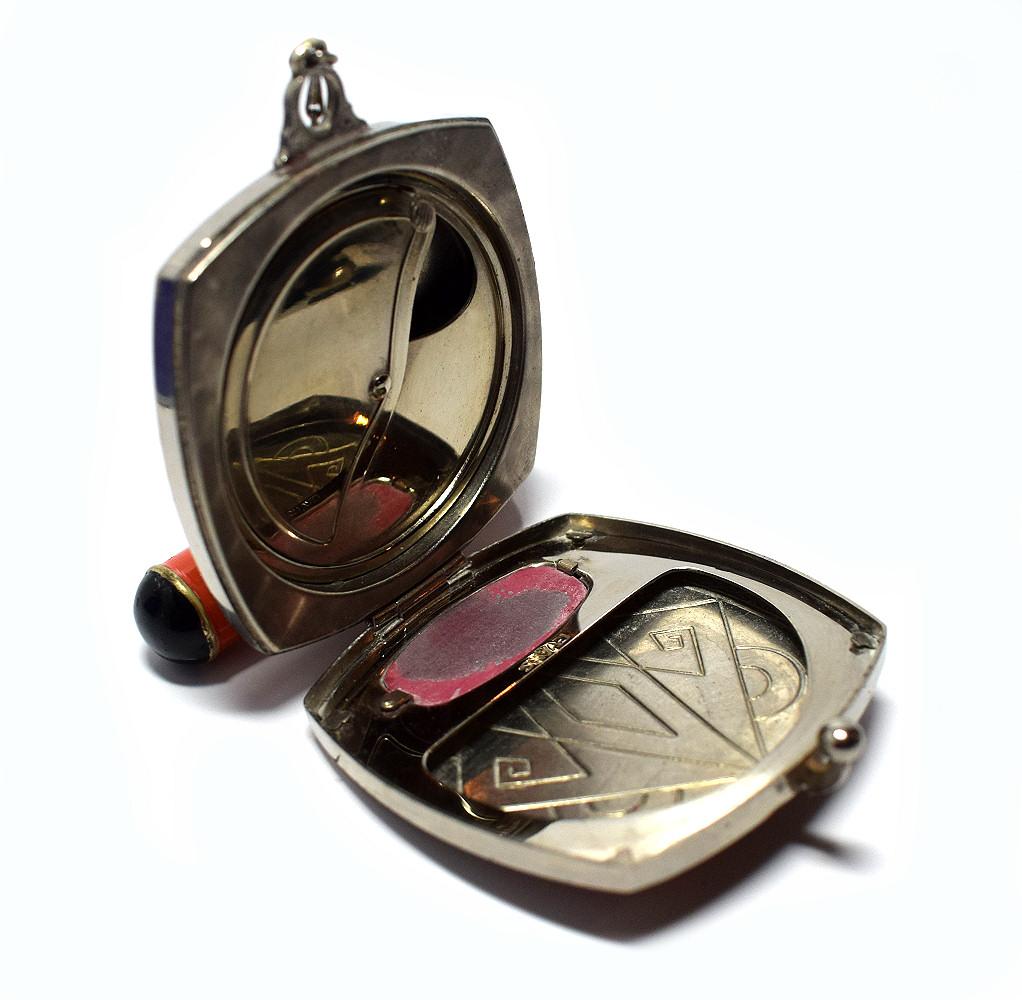 An Art Deco Evans of America silverstone vanity compact with geometric decoration in black and orange enamel decoration. An attached lipstick holder on a delicate chain links with the compact. The condition of this fabulous piece is truly remarkable