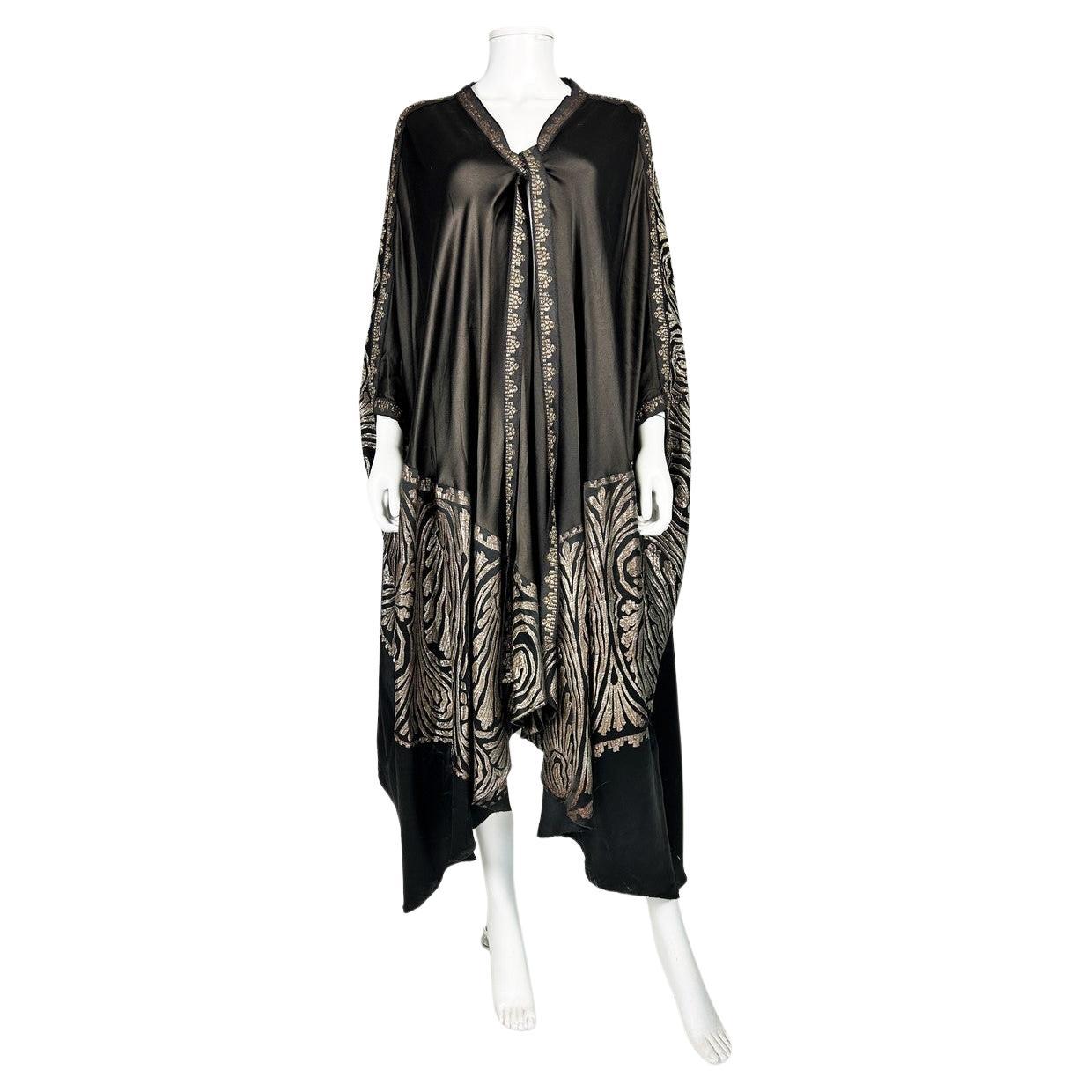 Circa 1920/1930

France

Beautiful orientalist-inspired Art Deco Burnous evening cape in black Duchesse satin and gold brocaded lamé dating from the 1920s. The cape has a wide amplitude and arm loops for a draped effect. A wide, reversible gold lamé