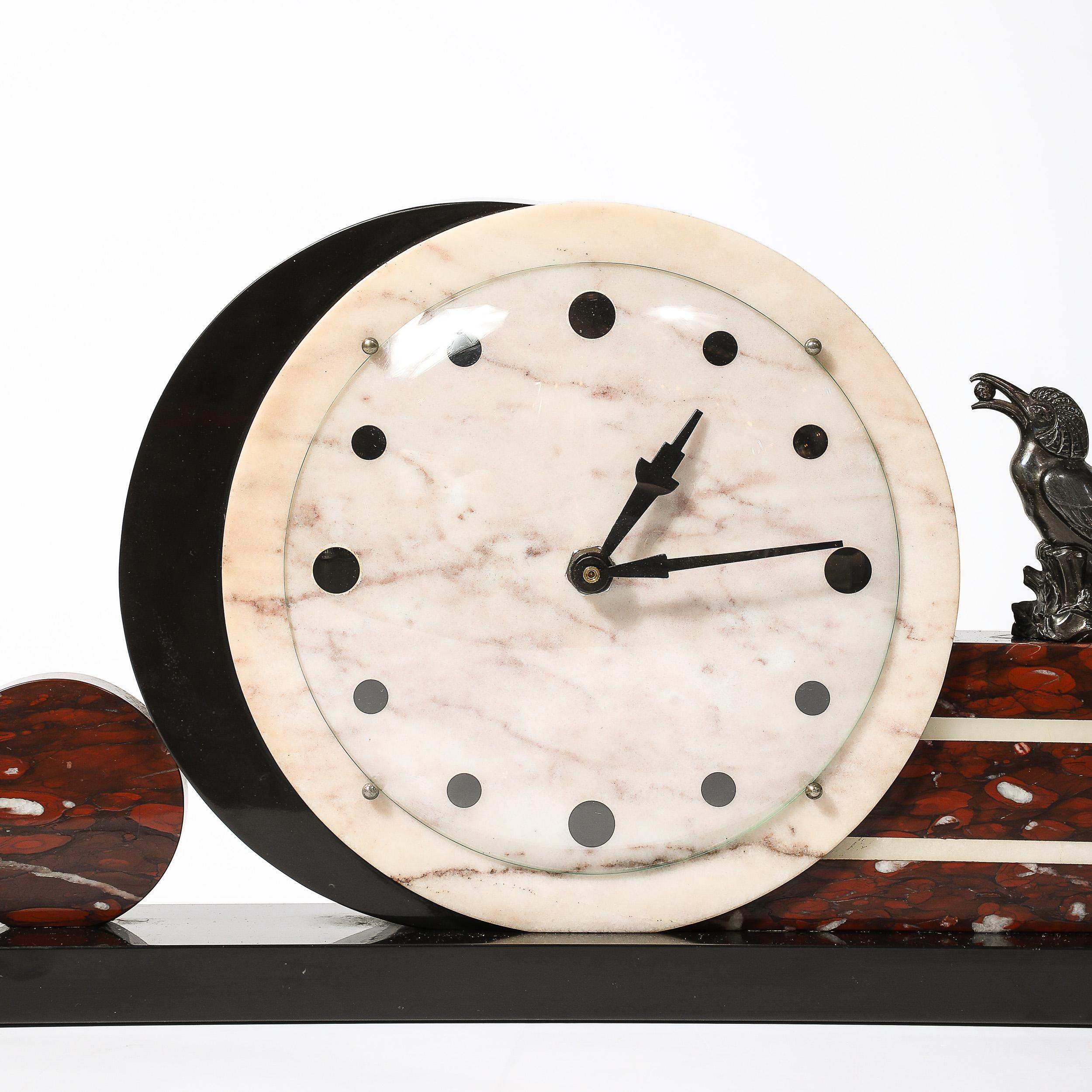 This highly geometric Art Deco Mantelpiece Clock in Nero Marquina marble, Sosalia Lucida Onyx, and Red Napoleon Marble W/ Bronze Sculptural Motif originates from France, Circa 1930. Features a round face in  marble with lovely grey textural