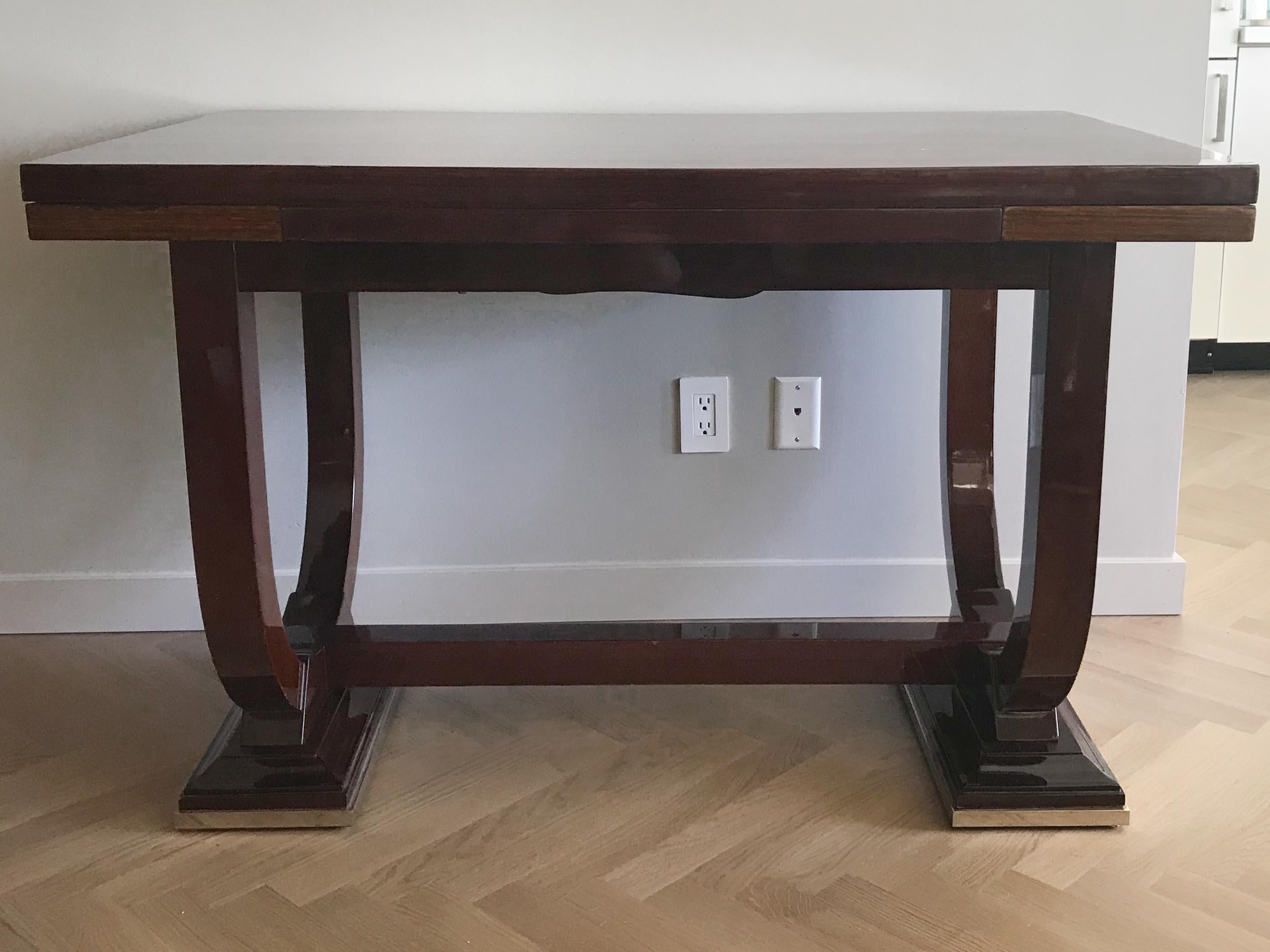 Art Deco dining or writing table in the manner of Jules Leleu. Expandable surface on U-feet resting on stylized plinths. Can be utilized as a dining table, serving table or a writing desk. Good condition, wear consistent with age and regular use,