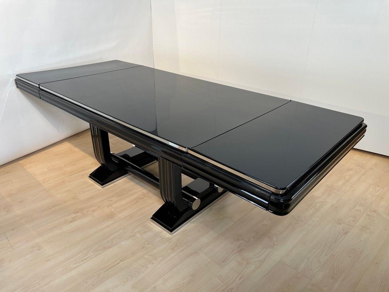Large Art Deco expandable / extending Dining Room Table from France, 1930s..
High-gloss black piano lacquer on solid mahogany wood. Polished stainless steel trims all around the plate.
Chrome-plated caps at the ends of the cylindrical intermediate