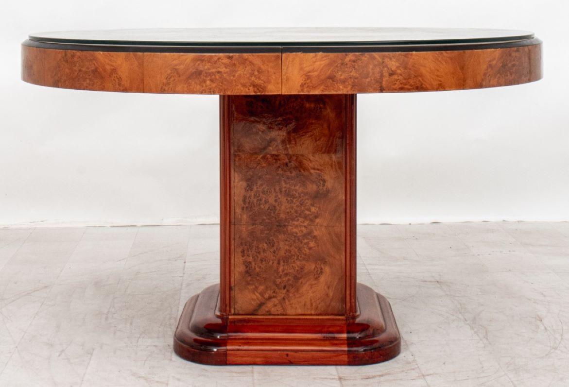 Art Deco Elm Burlwood Extending Pedestal Dining Table, the oval top with molded parcel ebonized edges above an extending mechanism with one leaf, over a square pedestal on rounded stepped plinth base. 

Dealer: S138XX