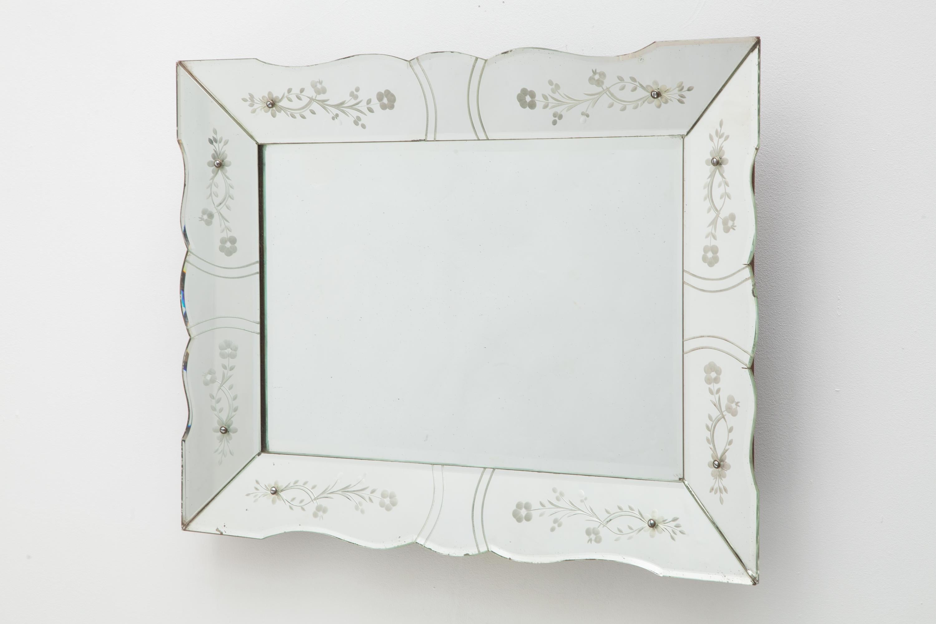 A beautiful Art Deco mirror with scrolled edge. Features a delicate etched floral motif. Horizontal rectangle shape. Backed by a wooden frame. France 1930s.