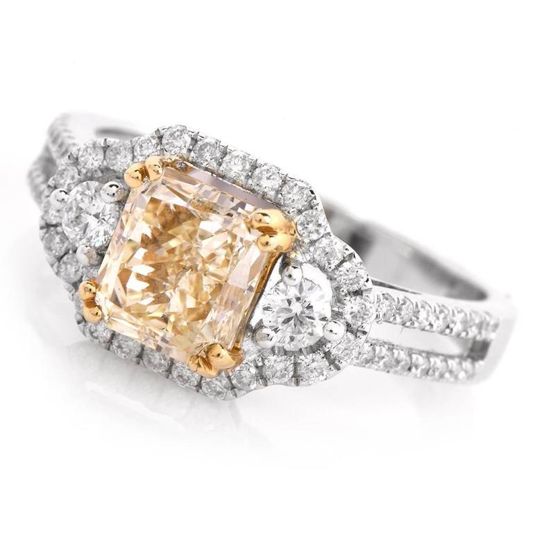 This style engagement ring is constructed in solid 18K white gold. Centering a fancy natural light yellow radiant cut diamond of approx. 2.04 carat,  Natural Yellow and VS1-VS2 clarity, secured by four yellow gold paw-prongs. Geometrically inspired