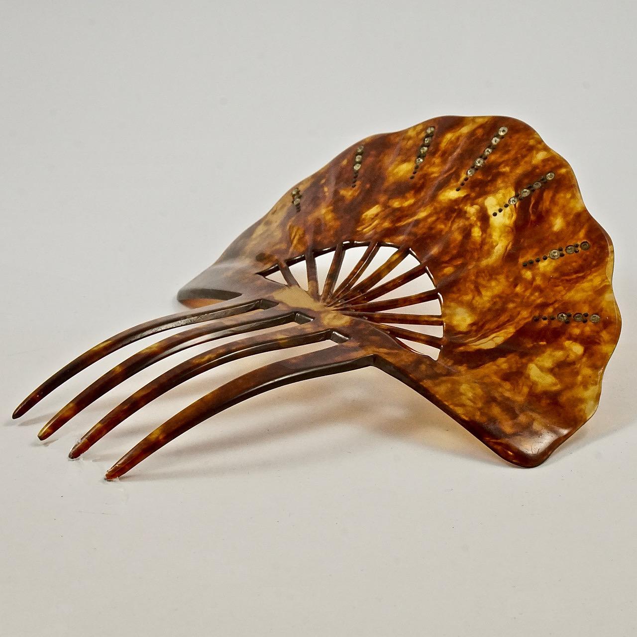 
Lovely Art Deco faux tortoiseshell four prong fan shaped hair comb with a scalloped edge, featuring clear faceted rhinestones and metal dot decoration. Measuring length 13.3cm / 5.2 inches by width 12.2cm / 4.8 inches. The hair comb is in very good