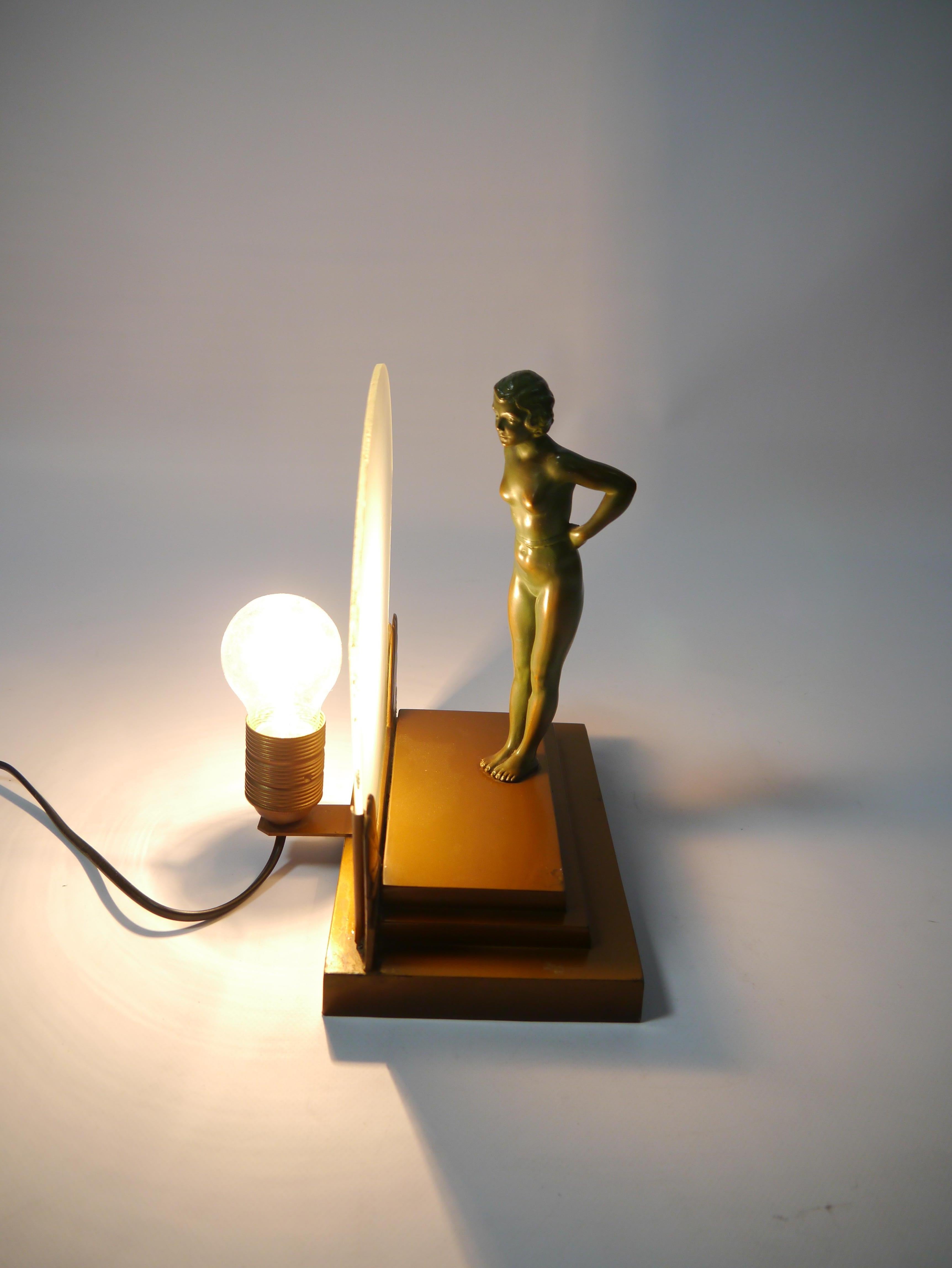 Art Deco figure lamp, showing a seminude bronze female figure standing on a podium and leaning towards a frosted glass screen. The figure can also be turned around 180 degrees. The figure shows delicate detailing and beautiful age related patina.