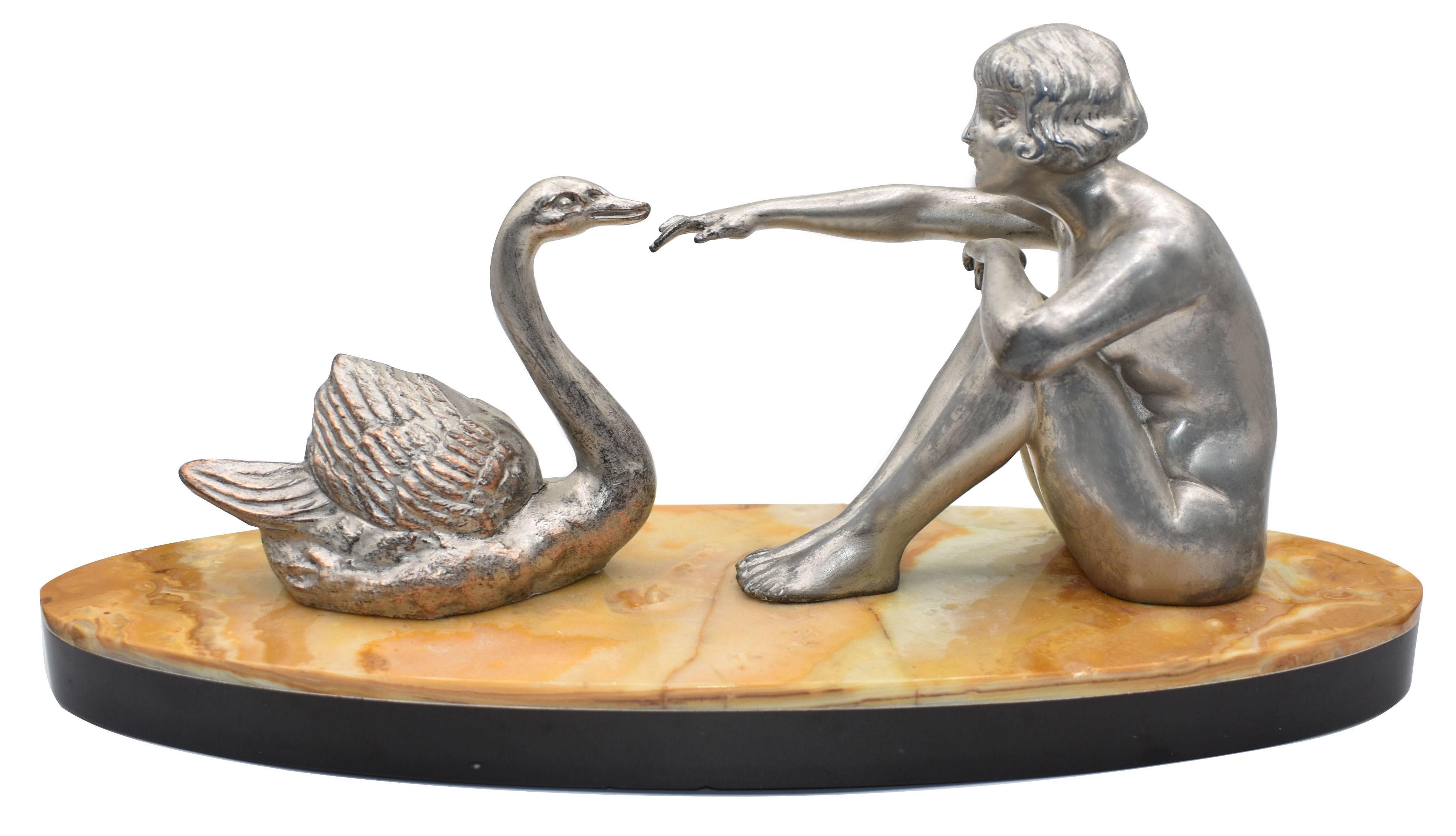 Very charming and original 1930s French figural group, features a young nude lady sat down reaching out to a swan, she has a styled hair cut of her era. The silvered group are beautifully and skillfully detailed, sat upon two-tone oval shaped marble