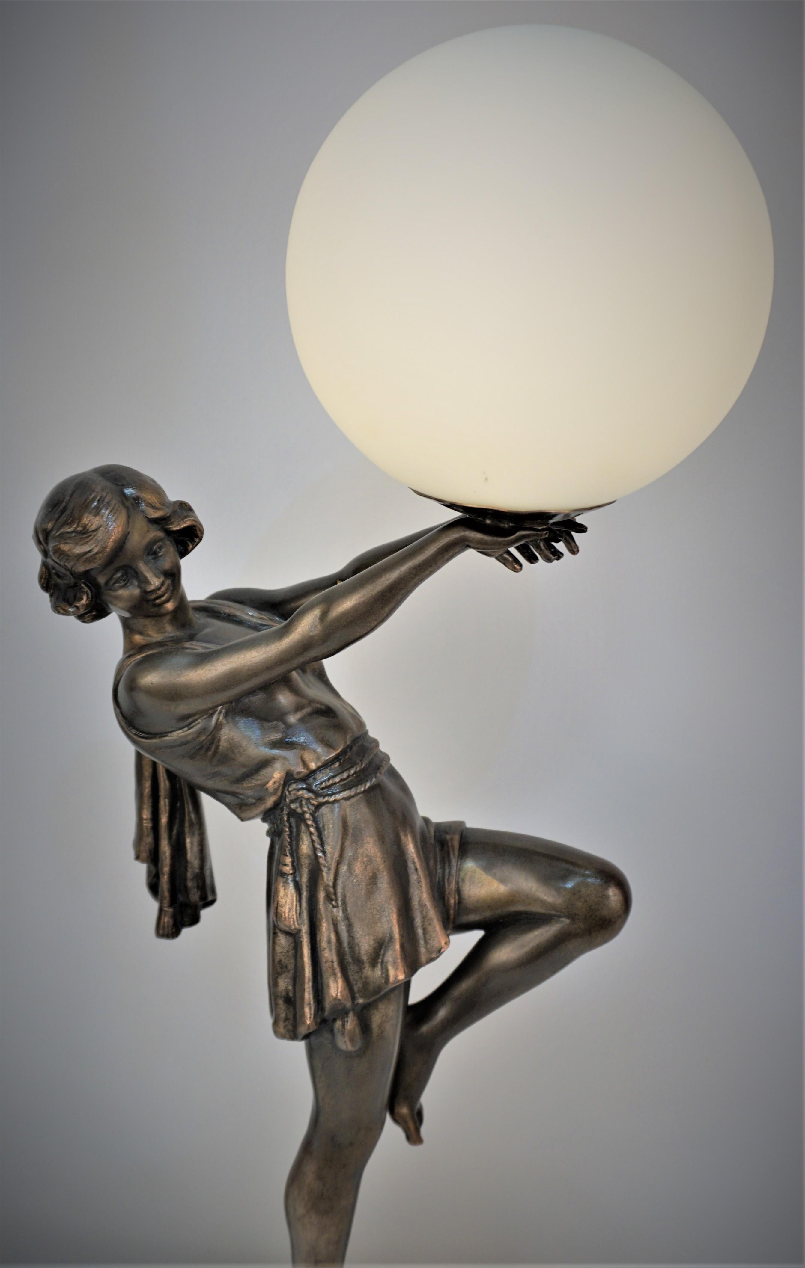 Art deco sculpture, standing on a marble base in dancing position holding a globe table lamp, by Fabrication Francaise Paris.