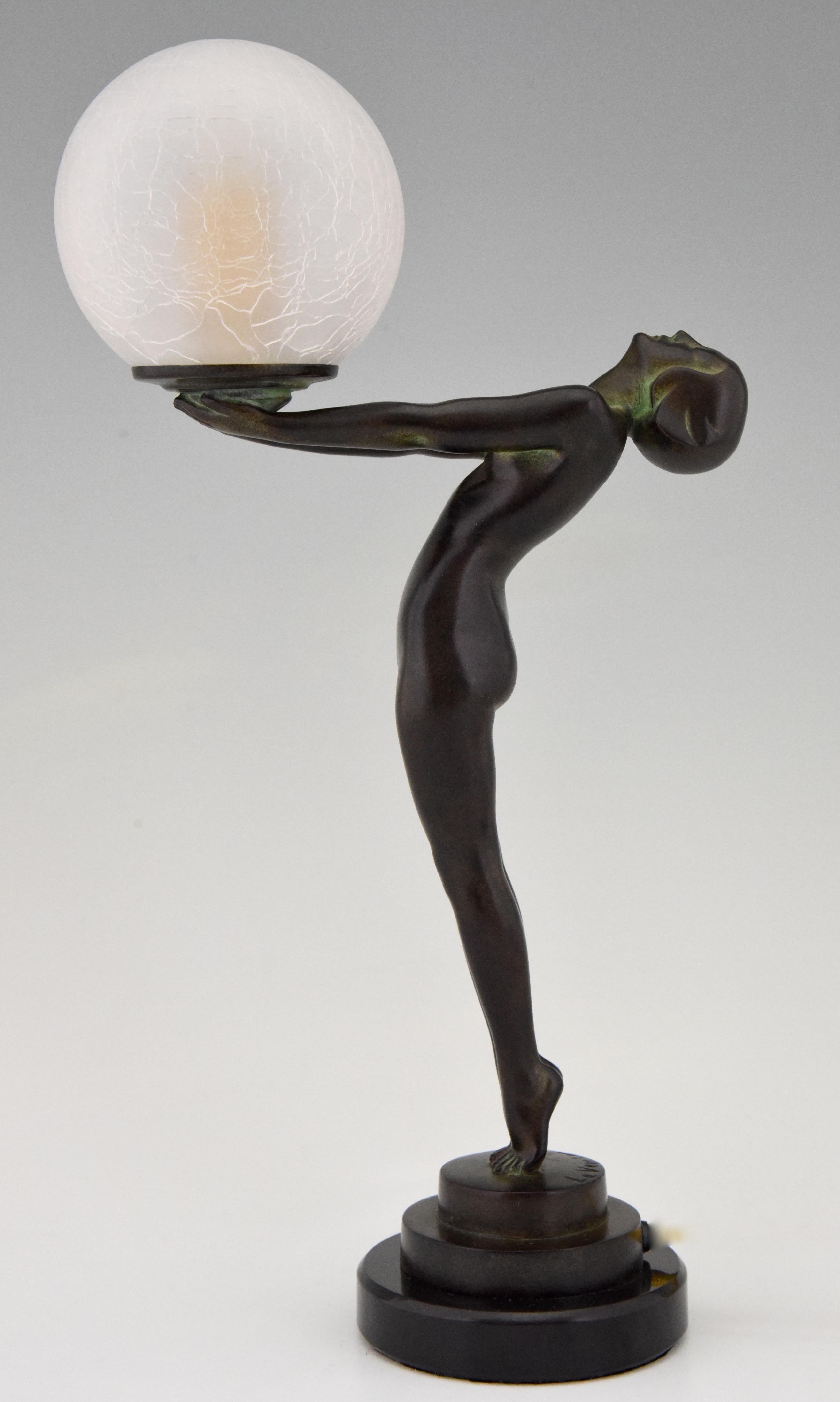 Art Deco style figural table lamp of a standing nude lady holding a glass globe.
This model is called Lueur lumineuse and is the smaller version of the iconic Clarté lamp by Max Le Verrier. 
The lamp is signed and has the Le Verrier foundry mark.