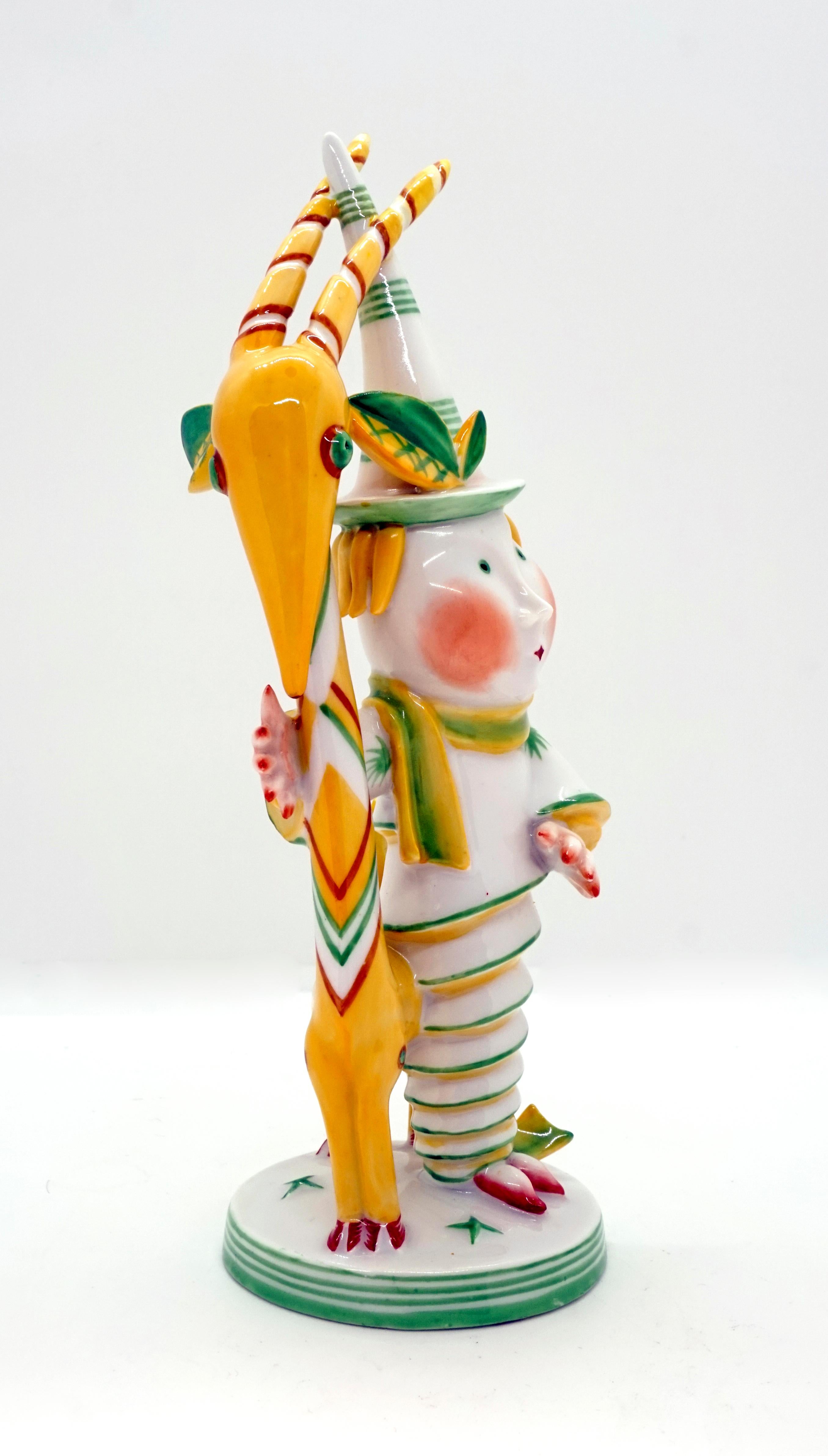 A man in a long dress wrapped like a spiral spring and a pointed hat hugs the animal with an excessively long neck standing next to him, with the horns and hat wedged together.
Painted in typical Art Deco style, in yellow, green and red, on a flat,