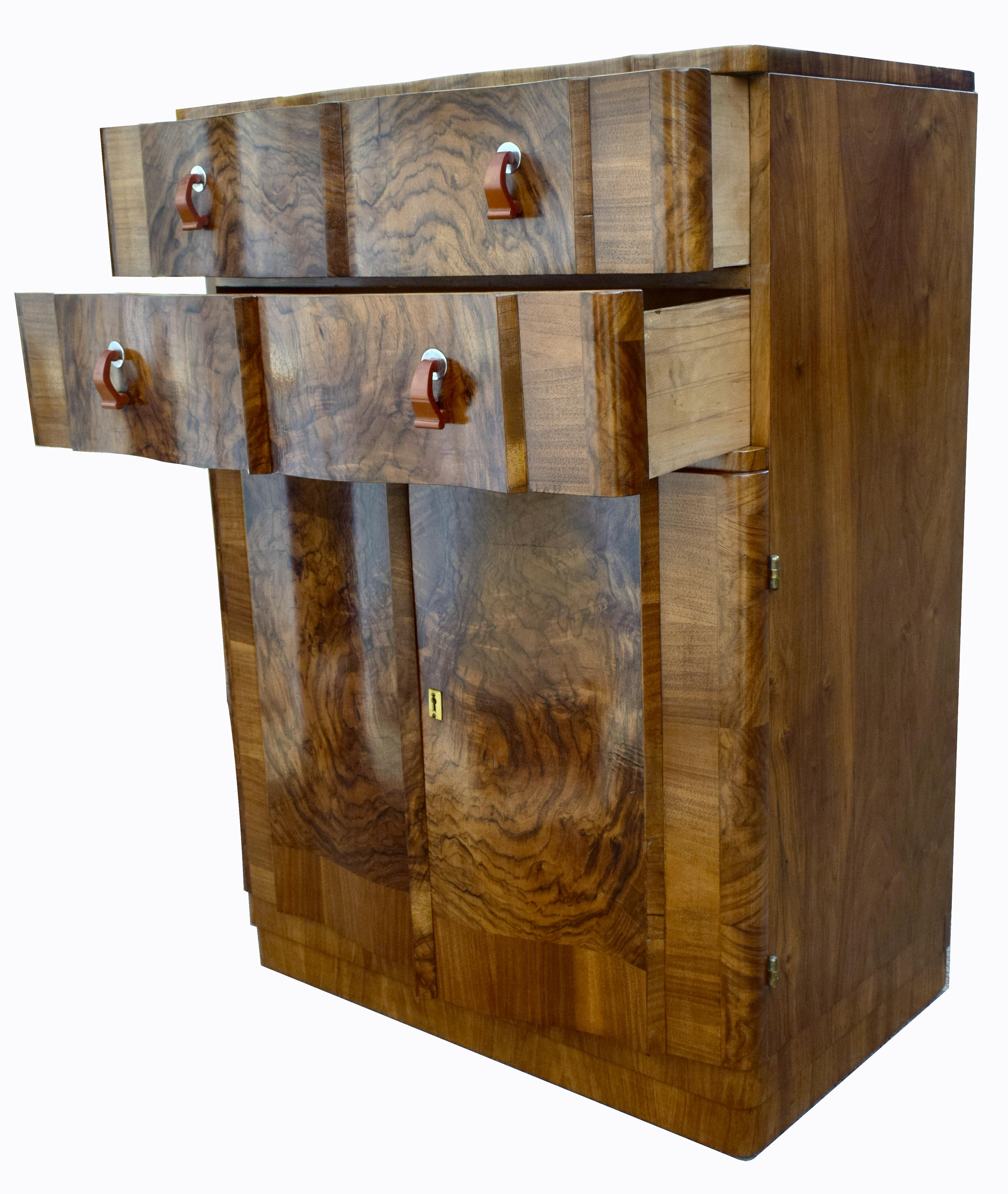 For your consideration is this English Art Deco burr walnut two-door, two drawer single-piece tallboy, circa 1930, boasting stunning mirror matched veneers and in excellent original condition. Comprising of an elegant Art Deco serpentine design with